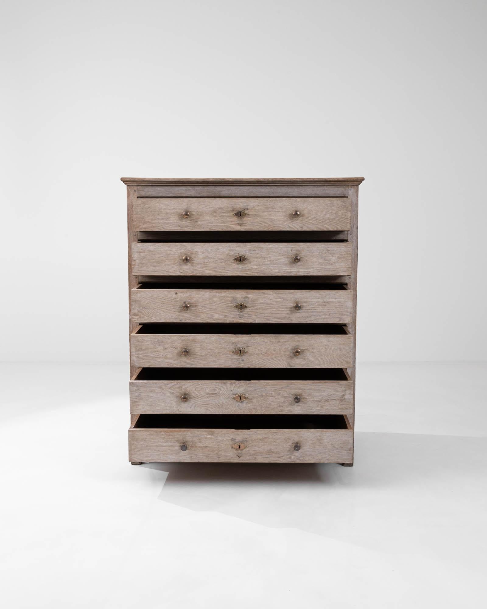 Infuse your space with the rustic charm and timeless elegance of this Early 20th Century Bleached Oak Chest of Drawers. Crafted with the sturdiness of seasoned oak, this piece features a bleached finish that highlights the natural grain and