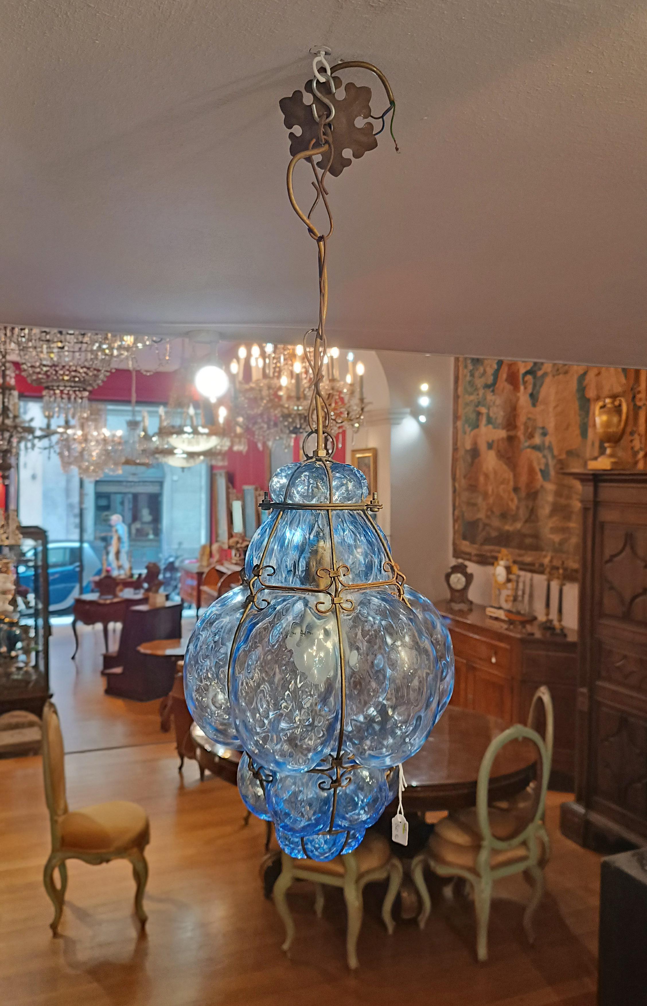 Beautiful blue Murano glass lamp blown into an iron structure. The peculiarity and beauty of this lamp lies in the shape and modeling of the glass, which is not smooth, thus allowing you to play more with the light. In addition to the iron