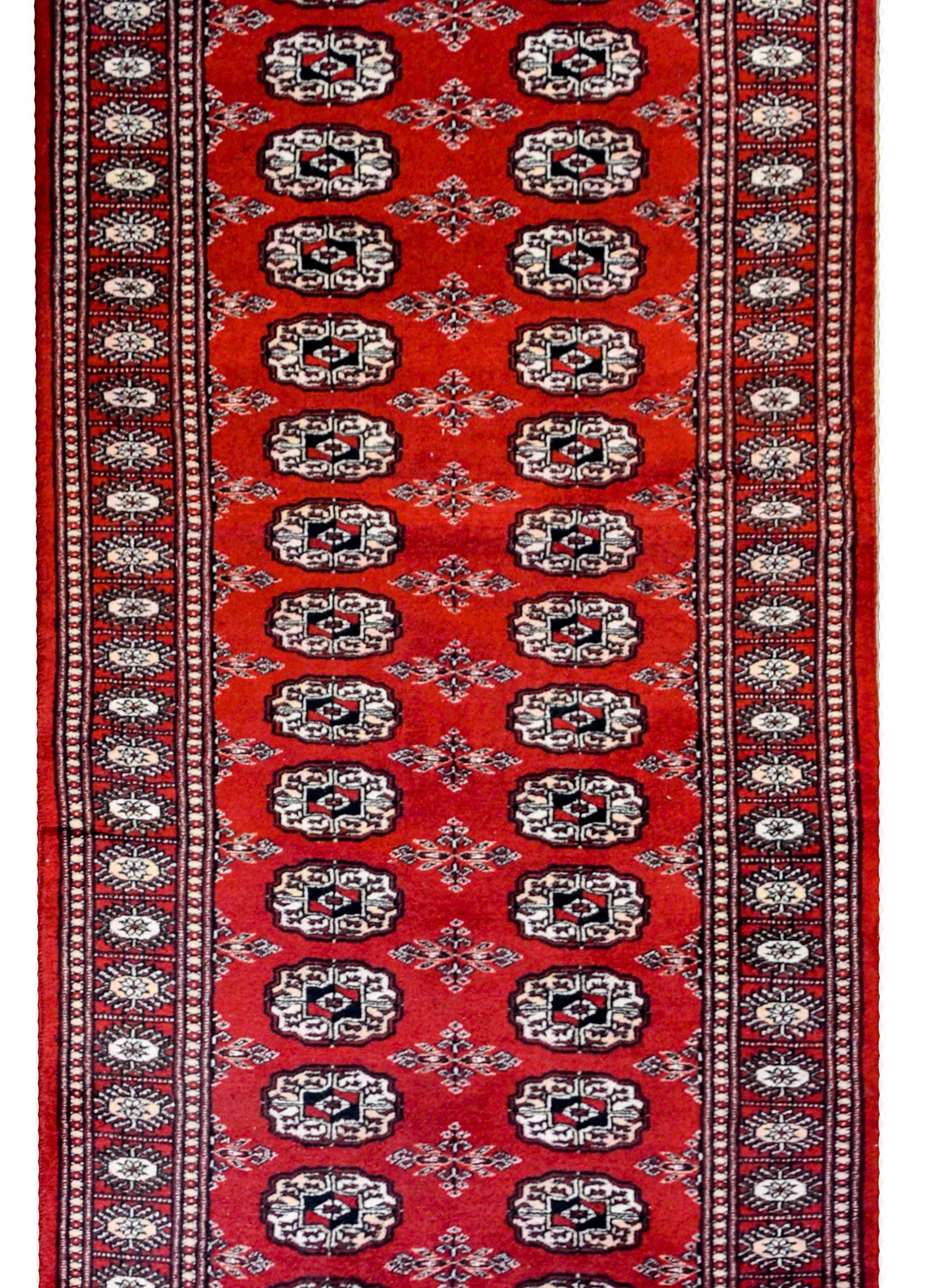 Ein wunderschöner pakistanischer Bokhara-Läufer aus dem frühen 20. Jahrhundert mit einem Allover-Muster aus kleinen Medaillons inmitten eines Feldes aus Blumenmedaillons, gewebt aus purpurroter, schwarzer und weißer Wolle. Die Umrandung ist einfach