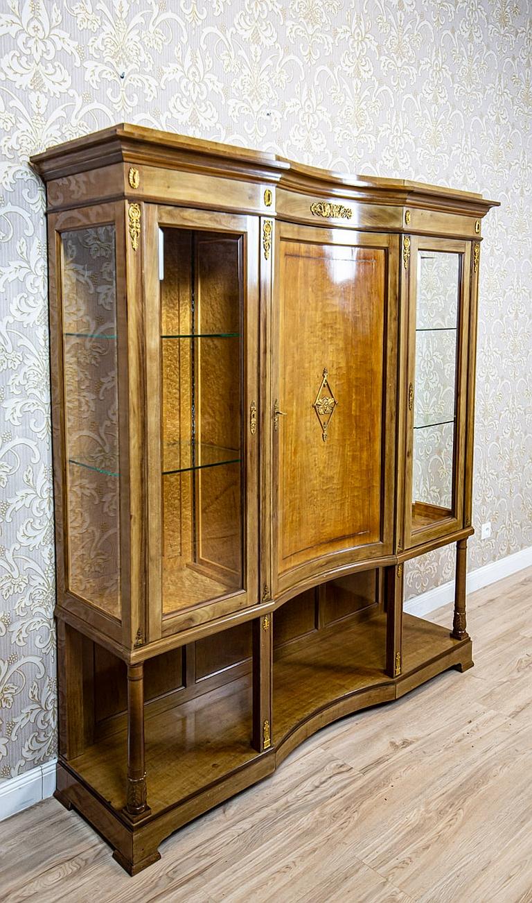Early 20th-Century Bookcase in the Empire Type with Brass Appliques

We present you a big three-leaf bookcase that resembles furniture in the Empire style.
It was manufactured before 1939.
This piece of furniture is supported on high legs which are