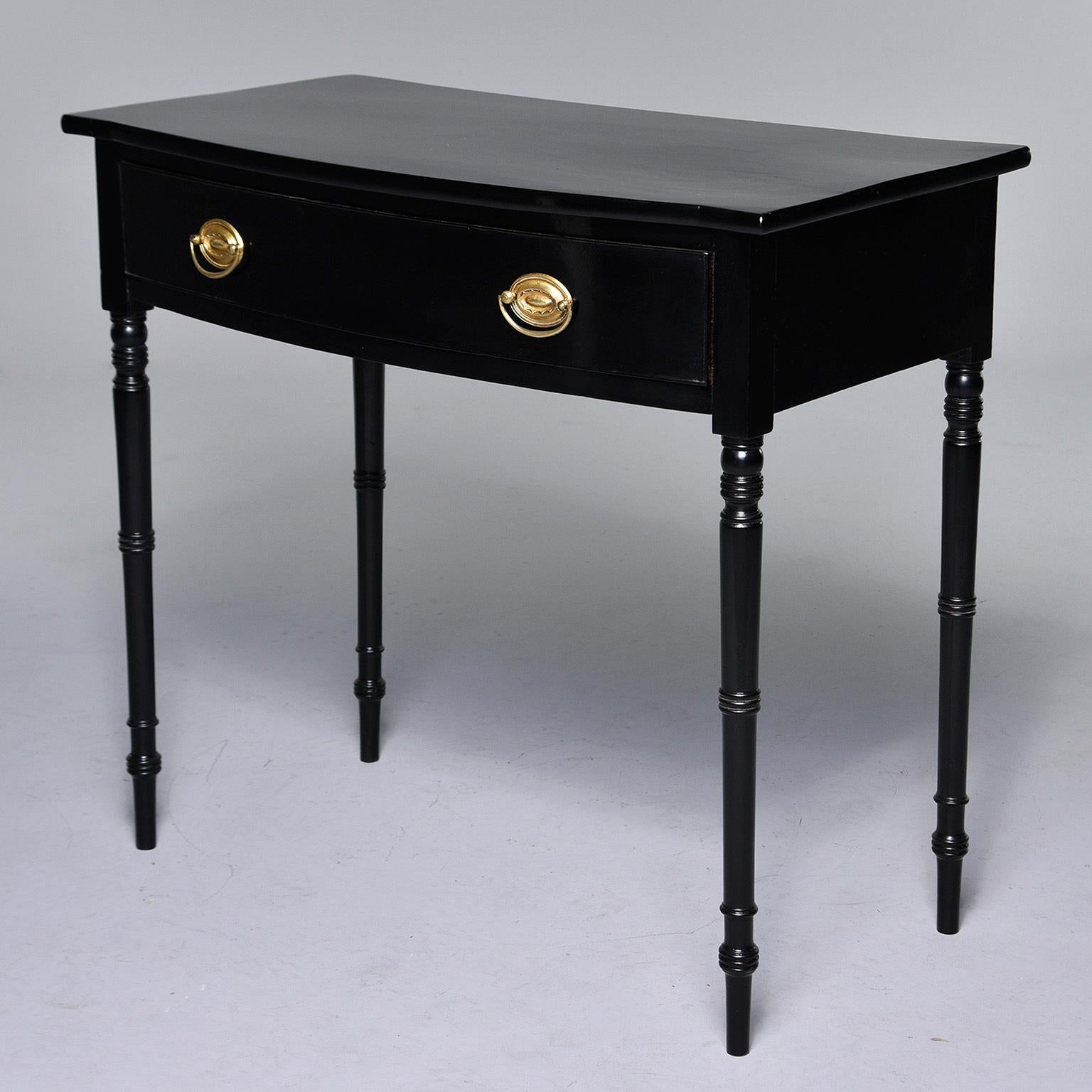 English mahogany side table with curved front, slender turned legs, single functional drawer with brass hardware and new, ebonized finish, circa early 1900s. Unknown maker.