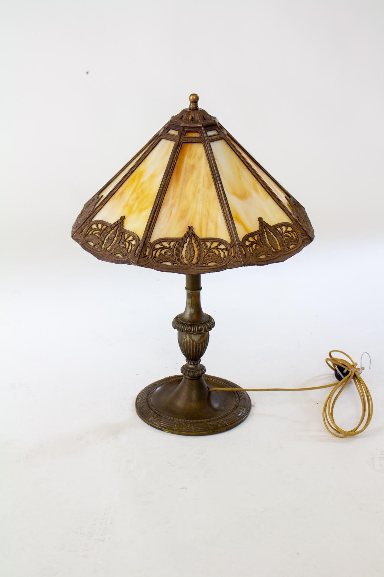Early 20th Century Bradley and Hubbard panel glass lamp. Eight sided flared shade with caramel glass. Base is cast metal with original bronzed finish. Both shade and base are marked Bradley and Hubbard. American, C. 1920

Condition: Original finish