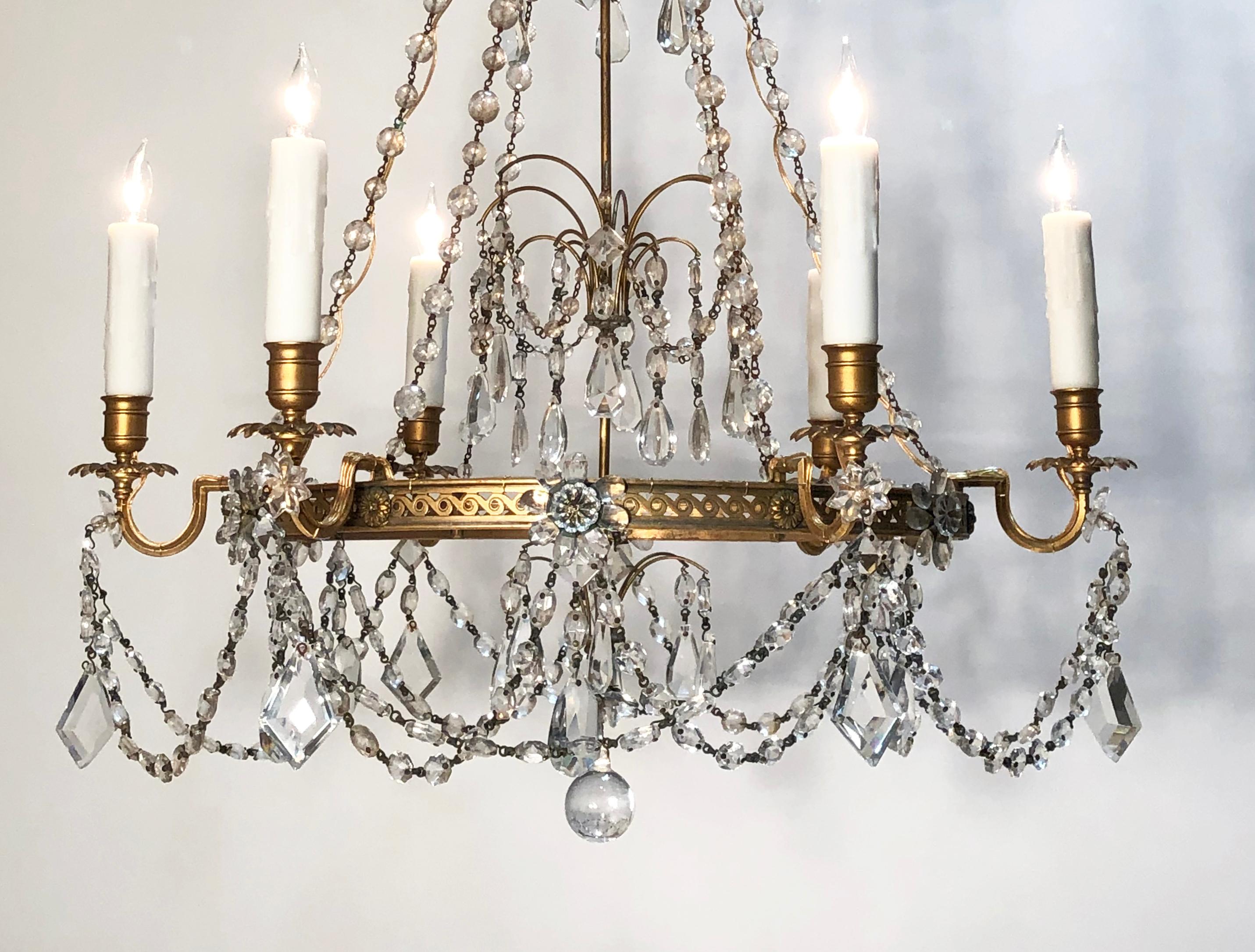 This beautiful early 20th century brass and crystal chandelier is attributed to Caldwell of New York. The chandelier is Regency in style featuring a wonderful pierced brass central ring. The chandelier has 6 electrified candle arms.