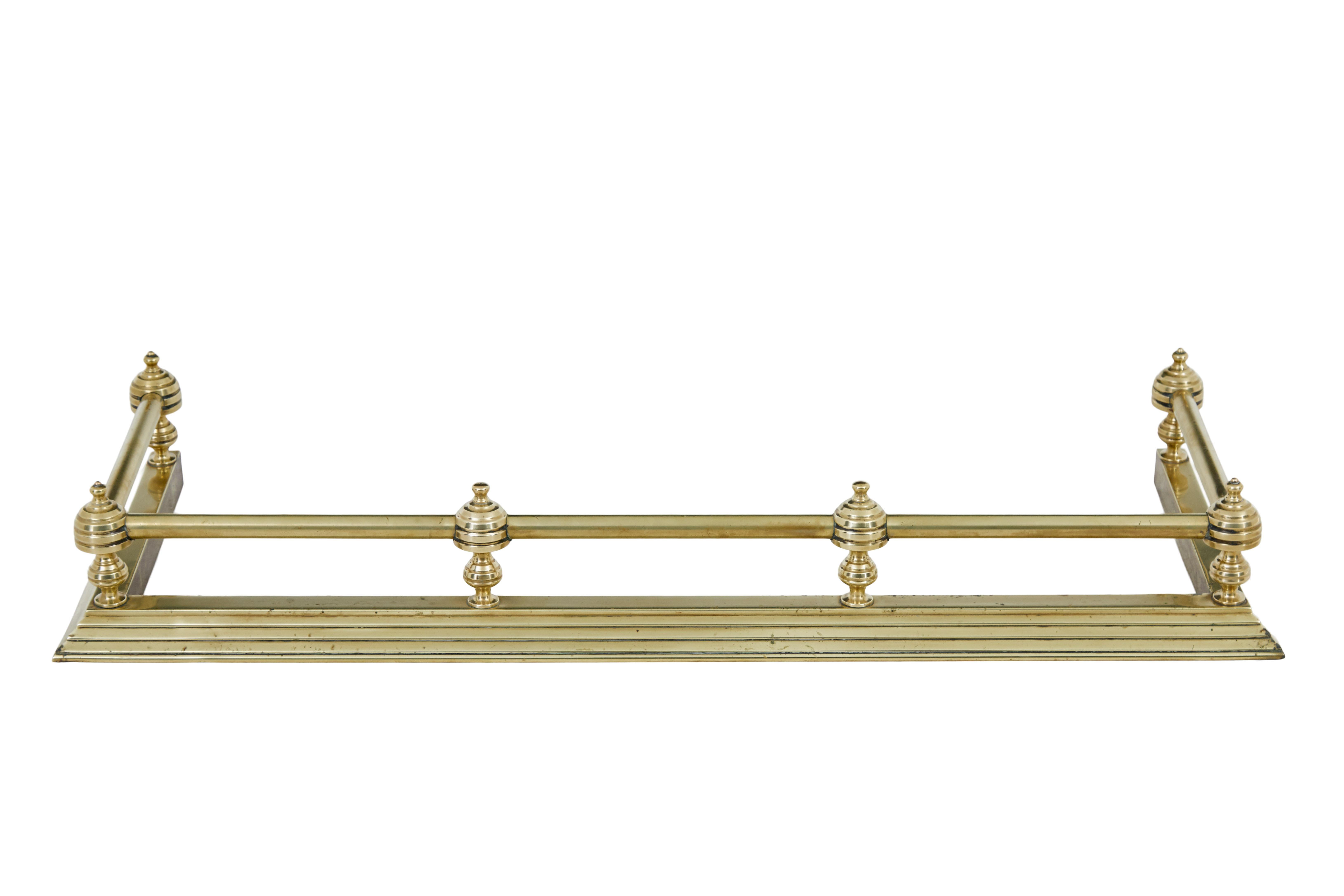 Early 20th century brass fireside fender circa 1900.

Elegant and simple brass fender.  6 turned finials linked by tubing which form an open rectangular shape.  Standing on a stepped plinth base.

Inside measurement: 42