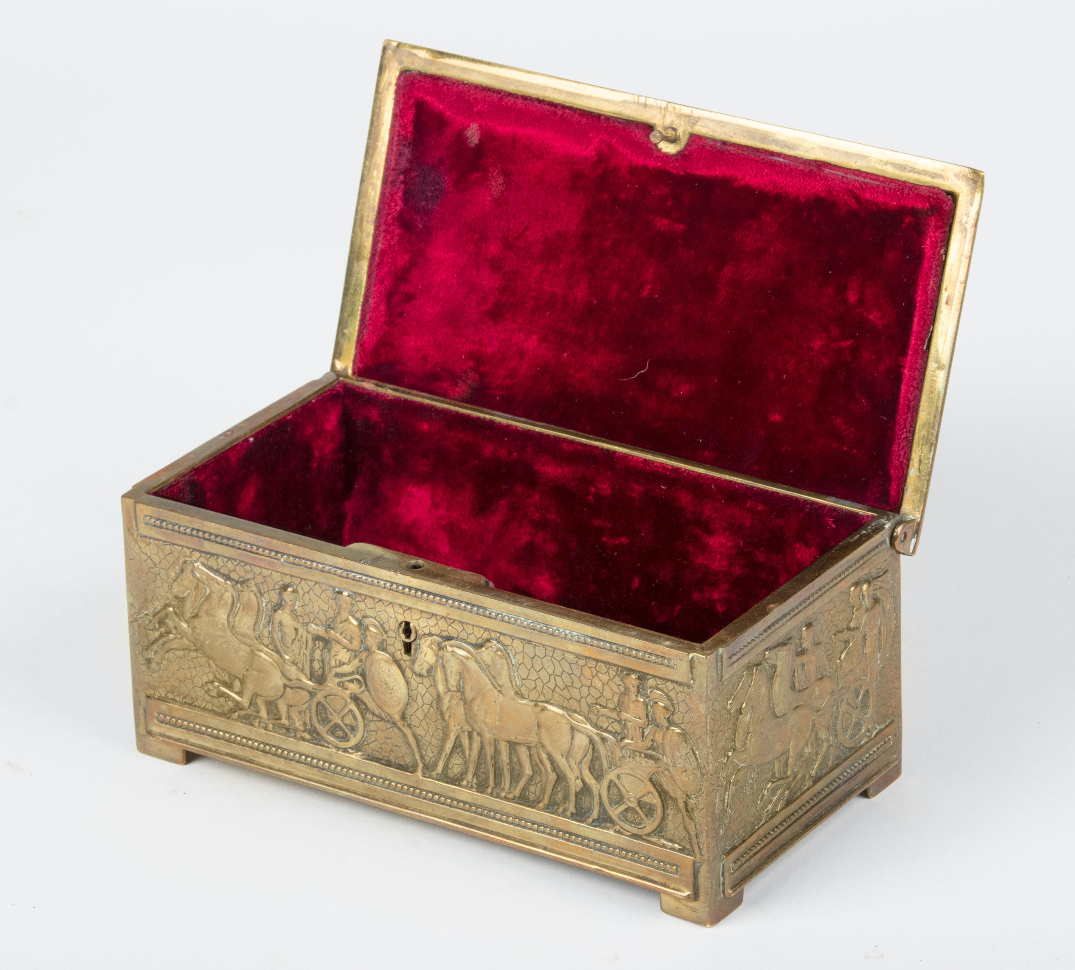 Beautiful old box, made of yellow brass, with images of the Classical Roman Empire. The interior is lined with red velvet fabric. The box dates from circa 1920-1930. Including key and working lock.