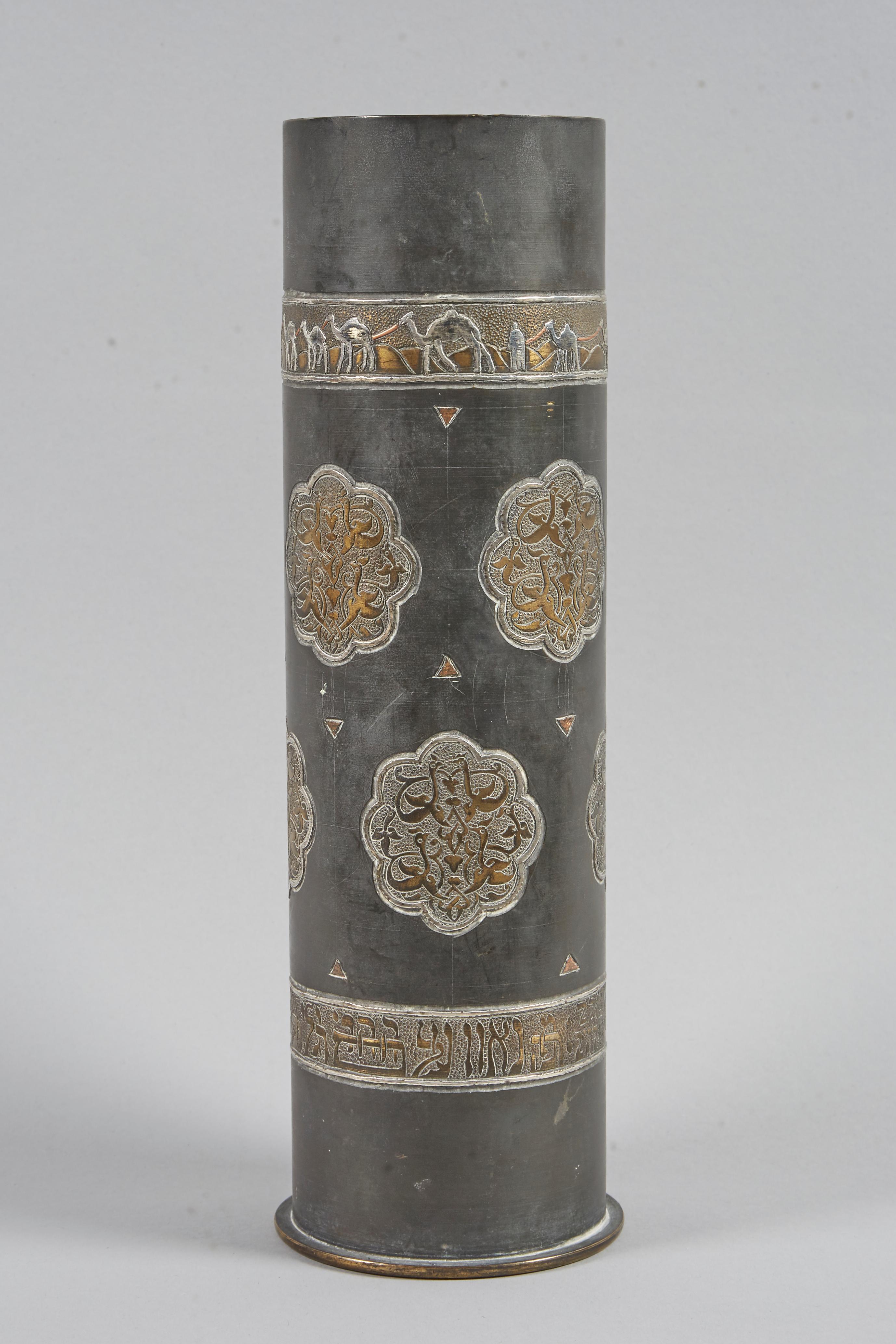 Artisan work made from a WWI shell case. Decorated with eight cartouches with six Islamic style birds inside. Inlaid with silver two strips; the top one depicting camel train in Damascened work. The Bottom strip engraved with Hebrew: 