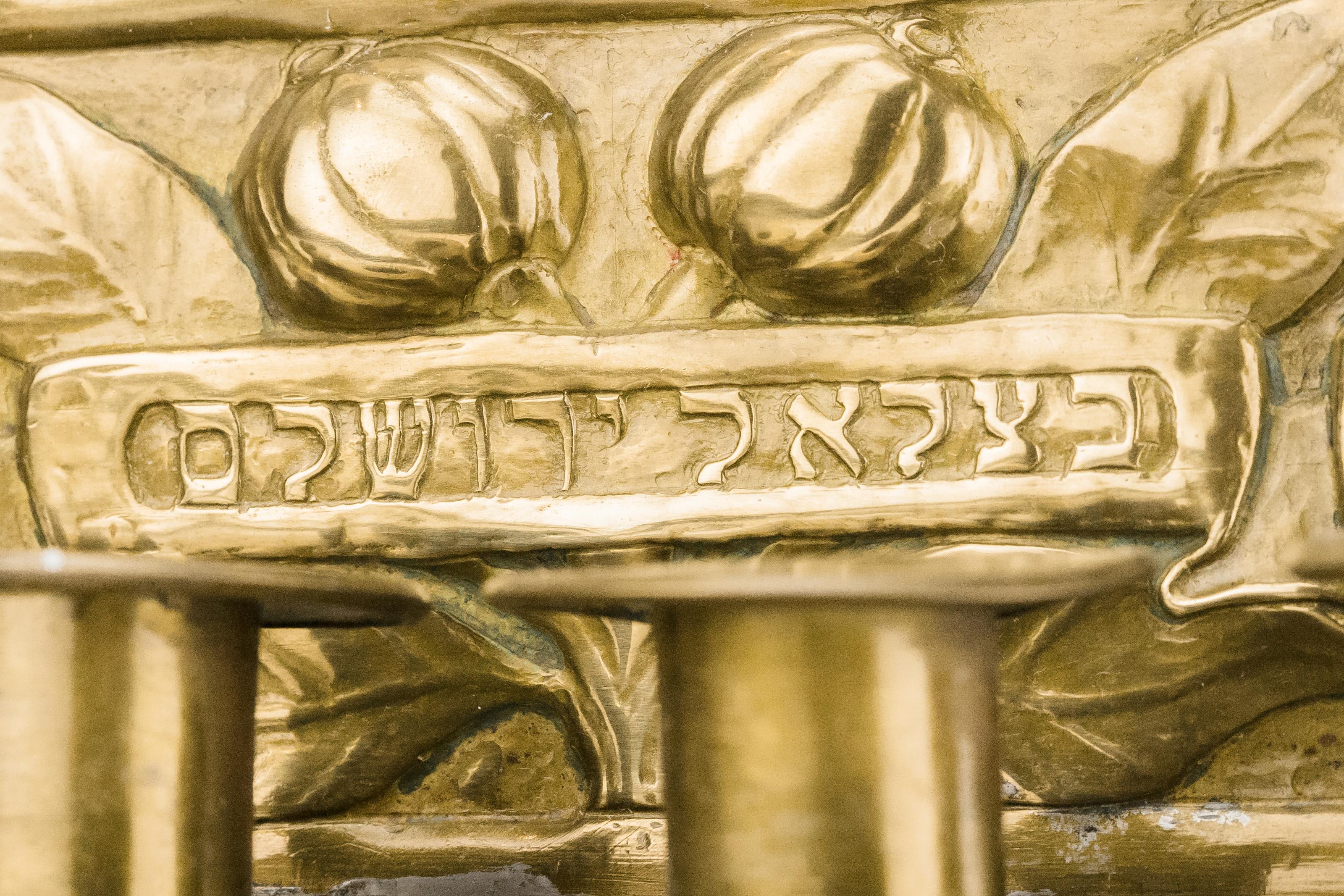 Large brass wall sconce, four light Shabbat lamp, Jerusalem, circa 1915.
Aside from the four candle holders, the decoration on this piece was entirely worked by hand, in both repousse and chasing. Shaped backplate with hand-hammered motifs of grape