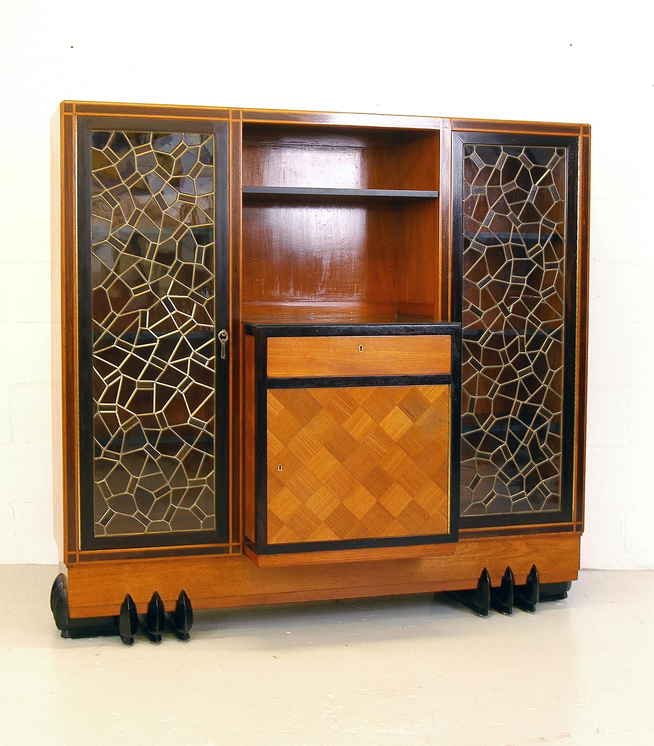 Unusual early 20th century breakfront buffet. Constructed entirely from teak and ebony, and standing on a pair of outrageous ‘clawed’ feet, with full height ebony inlay down each side.
The fabulous leaded mosaic doors are made from glass and ebony