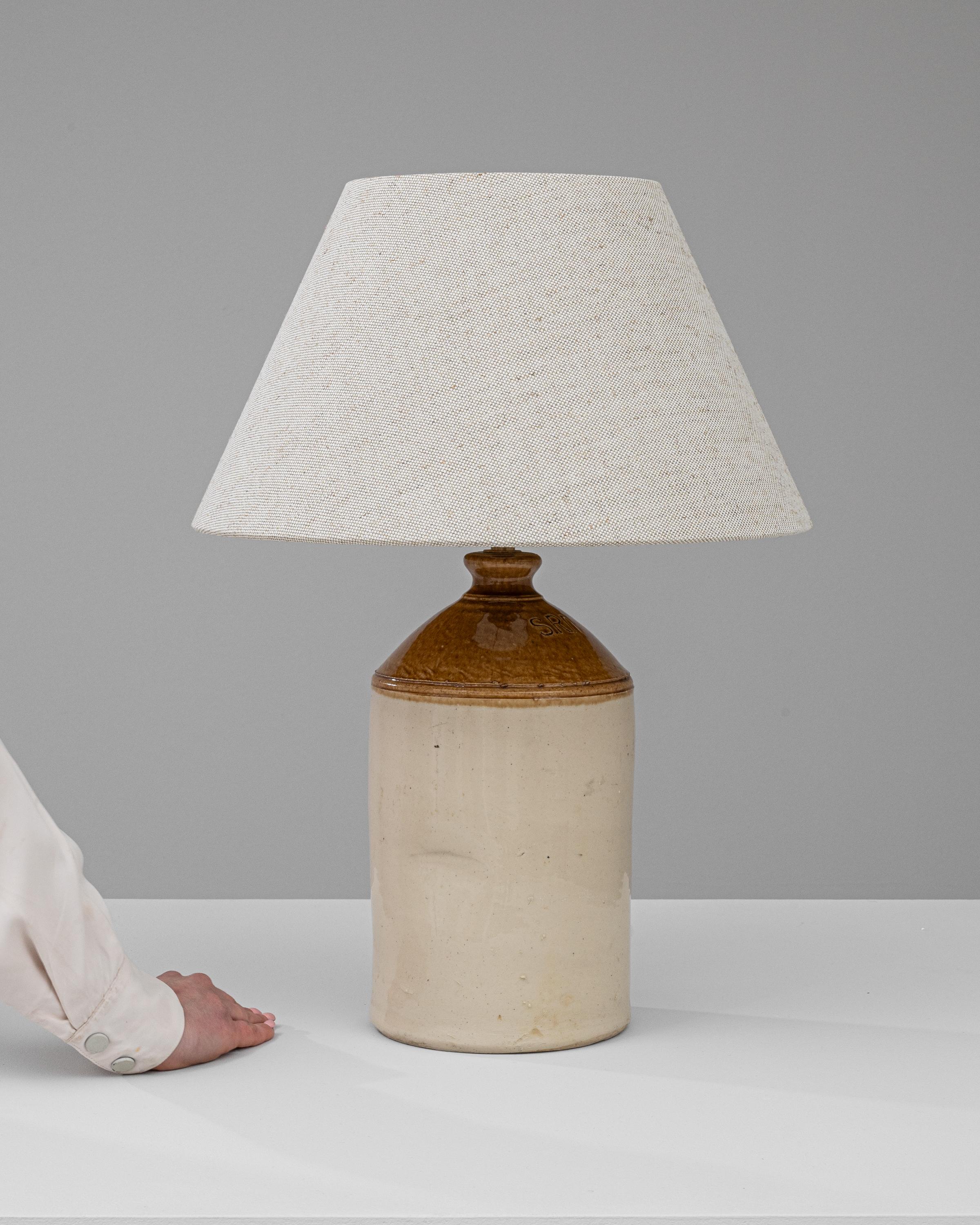 Discover the charm of the past with this Early 20th Century British Ceramic Table Lamp. Crafted with the finesse of yesteryear's artisans, this lamp boasts a sturdy, two-tone ceramic base that evokes the rich, earthen tones of the English