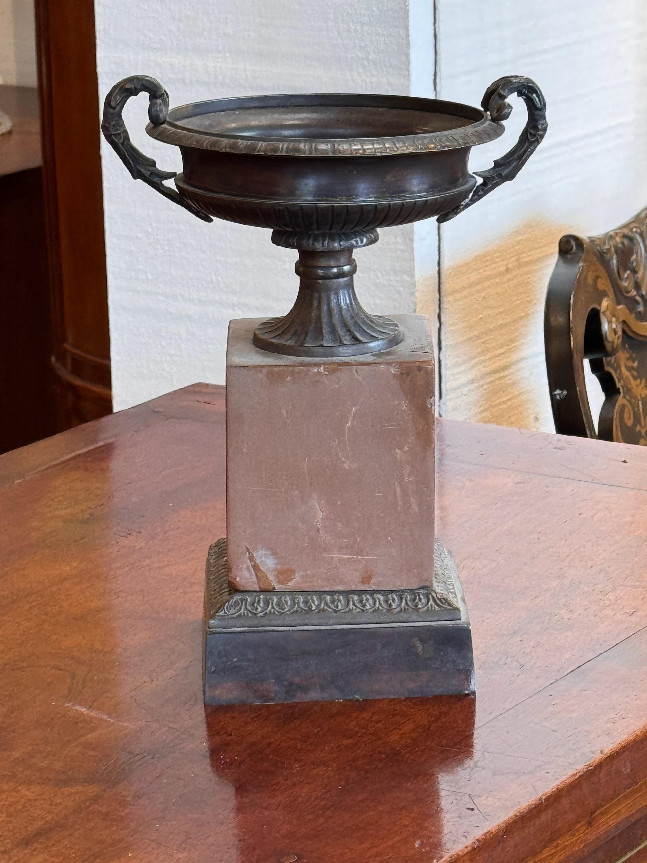 Tazza en bronze de style néoclassique du début du XXe siècle, avec une coupe peu profonde aux détails cannelés et des poignées élégamment incurvées, ornées de motifs classiques. La base en marbre complète la patine de bronze foncé, ajoutant à son