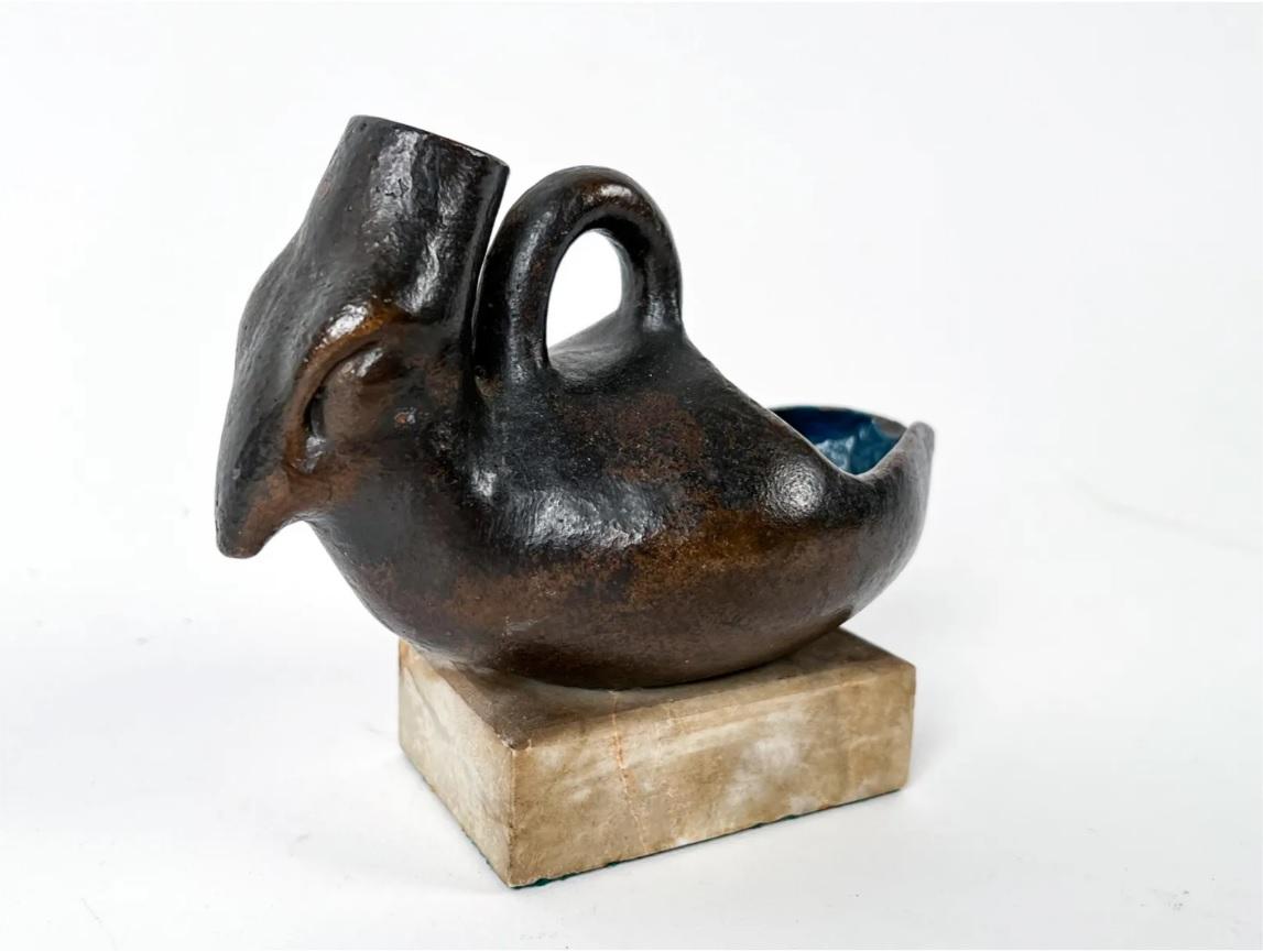 Unmarked bronze bird pitcher sculpture. Open back with spout on the head and loop on top. Interior painted blue. Mounted on marble base. 

Dimensions: (Overall) H 5