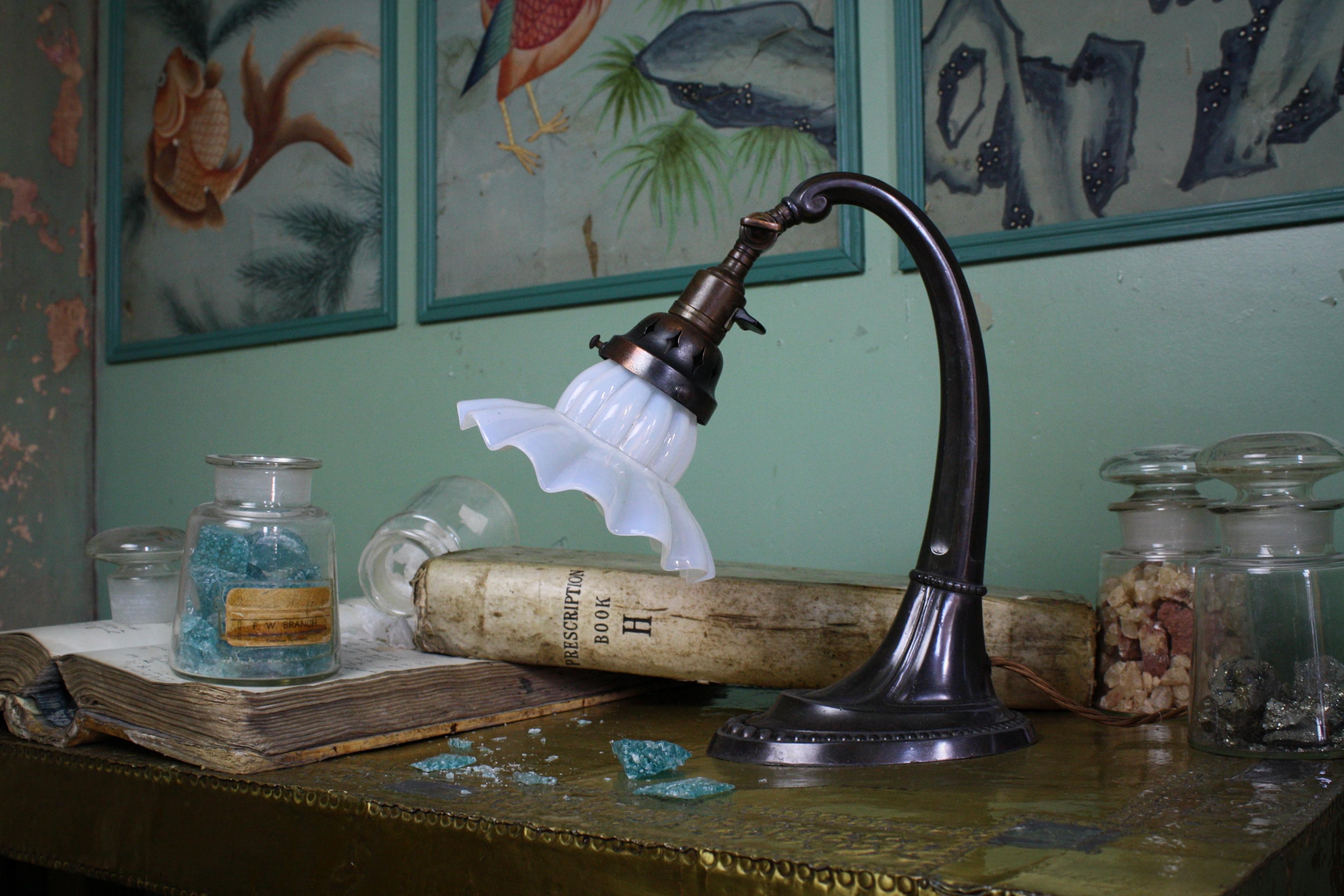 A stylish adjustable bronze and copper desk lamp, with a glass fluted white Vaseline shade.

Lightly cleaned and waxed, retaining its oxidised patina. Re-wired with antique style three core flex but not PAT tested. 

Has its original working