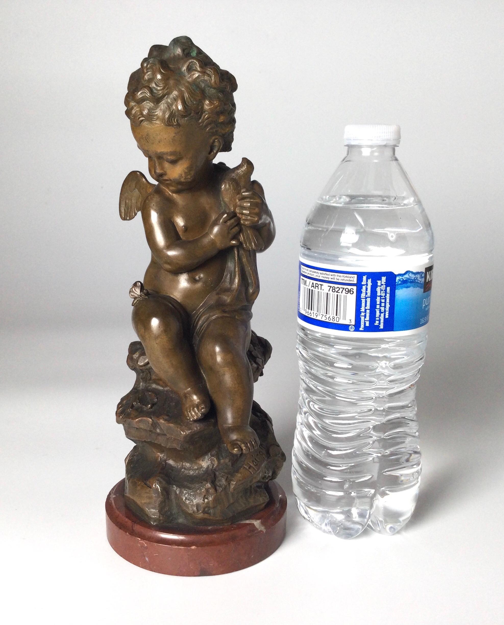 Bronzo firmato della fine del XIX secolo raffigurante un putti con colomba. La patinatura originale della scultura in bronzo finemente fusa con base in marmo battuto. Firmato Heiagle vicino alla parte inferiore.