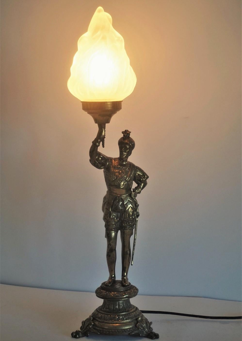 Candélabre en bronze massif, sculpture de chevalier en laiton, converti par la suite en lampe de table électrifiée, avec un grand abat-jour en verre dépoli en forme de torche.
Elle s'adapte à l'ampoule E27 d'Edison.
Hauteur totale : 23.75 in (60