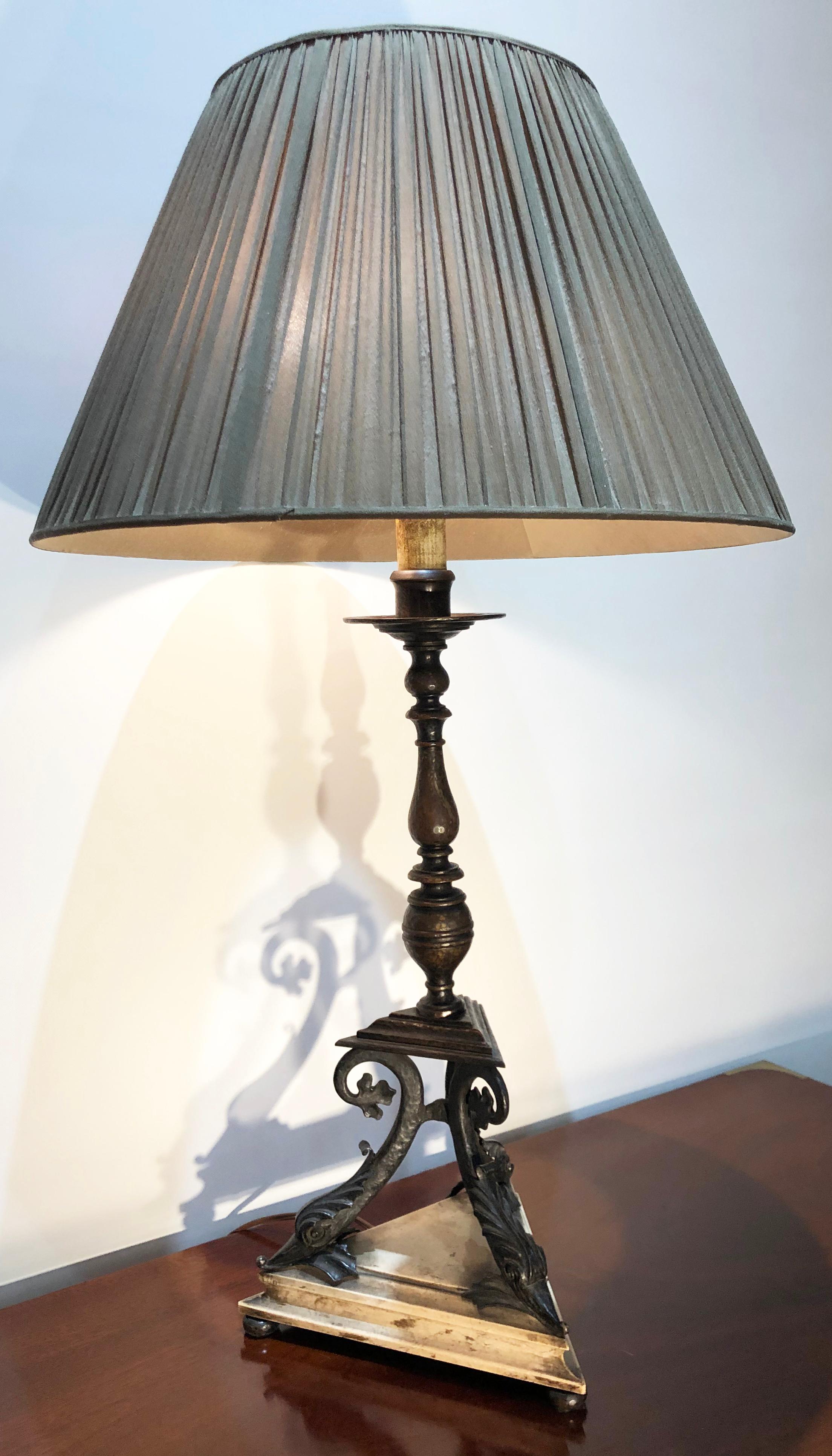 This early 20th century bronze mounted table came from the Estate of Peggy and David Rockefeller. Attributed to E.F. Caldwell, circa 1910. Wonderful dolphin motif at the base of the lamp. The bronze lamp is mounted to a wooden base with 3 bronze
