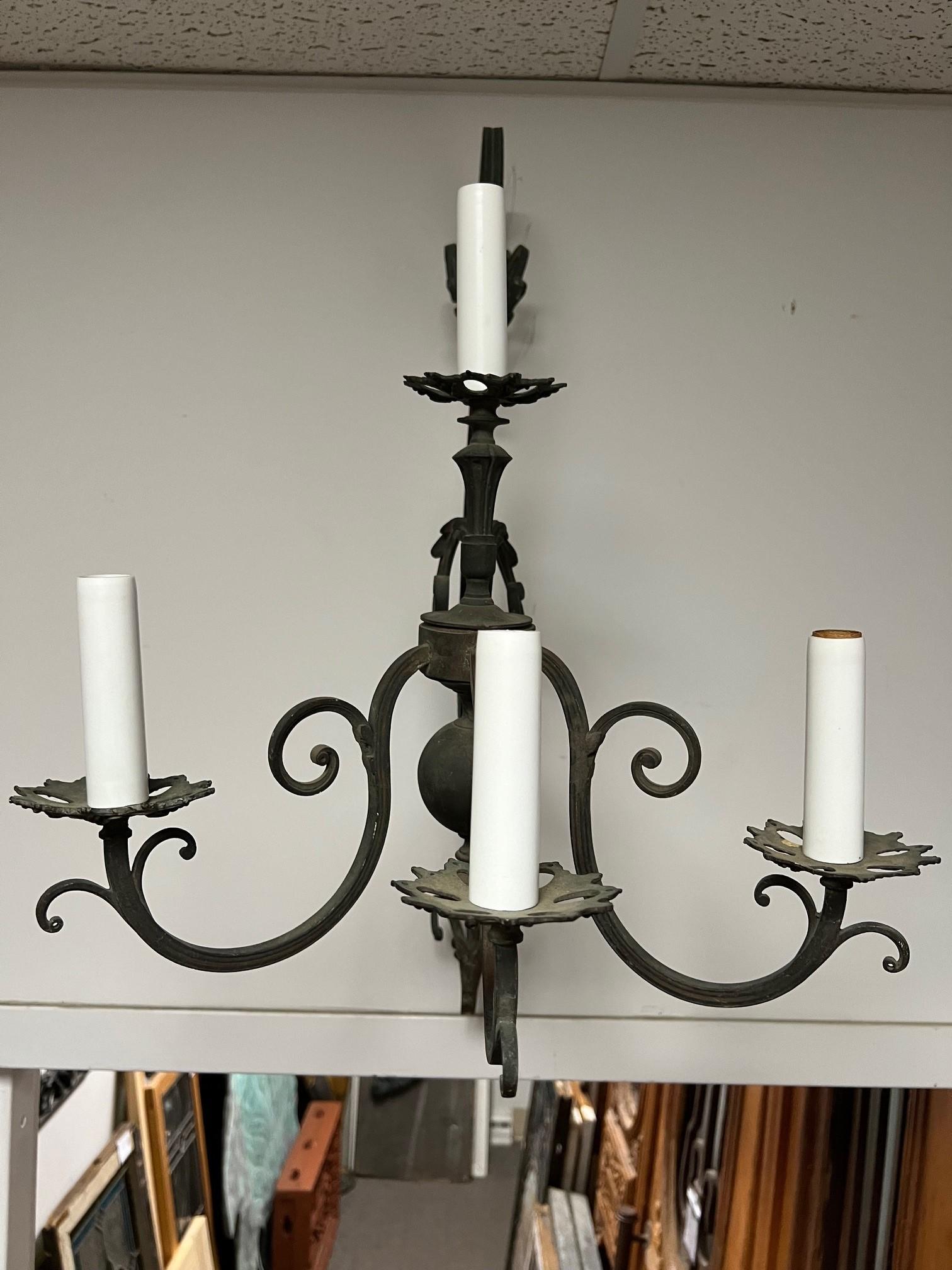 Aplique de pared de bronce de principios del siglo XX con tres brazos y cuatro luces. Se trata de un bello y elegante candelabro con sus tres brazos y su ménsula con volutas. El candelabro ha sido recableado y está en buenas condiciones de