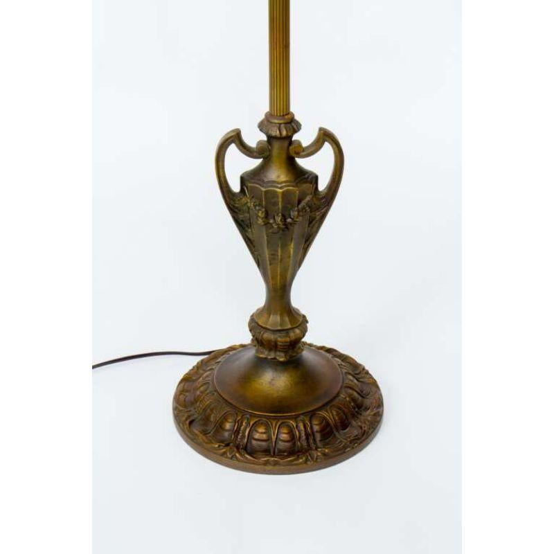 A traditional floor lamp made from a combination of cast iron and brass elements. Lovely scallop design base with a cast iron urn design. This lamp has an unusual break halfway up the stem that can hold four crystals or tassels. Made in the US C.