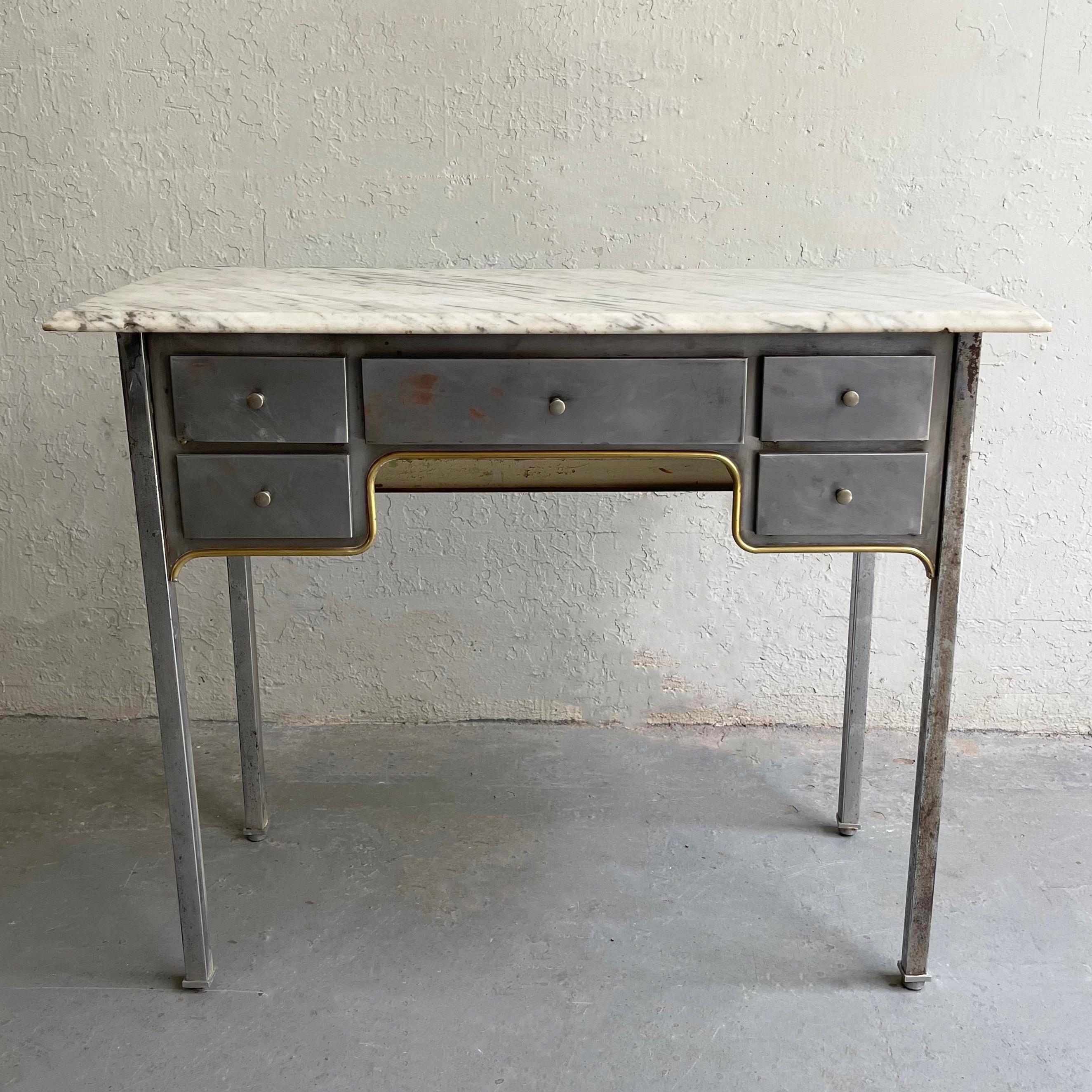 Early 20th century, industrial, brushed steel desk features a contrasting white marble top with beveled edge and five drawers with brass trim underneath them. This petite piece works beautifullly as a small desk, a vanity or entryway table. The