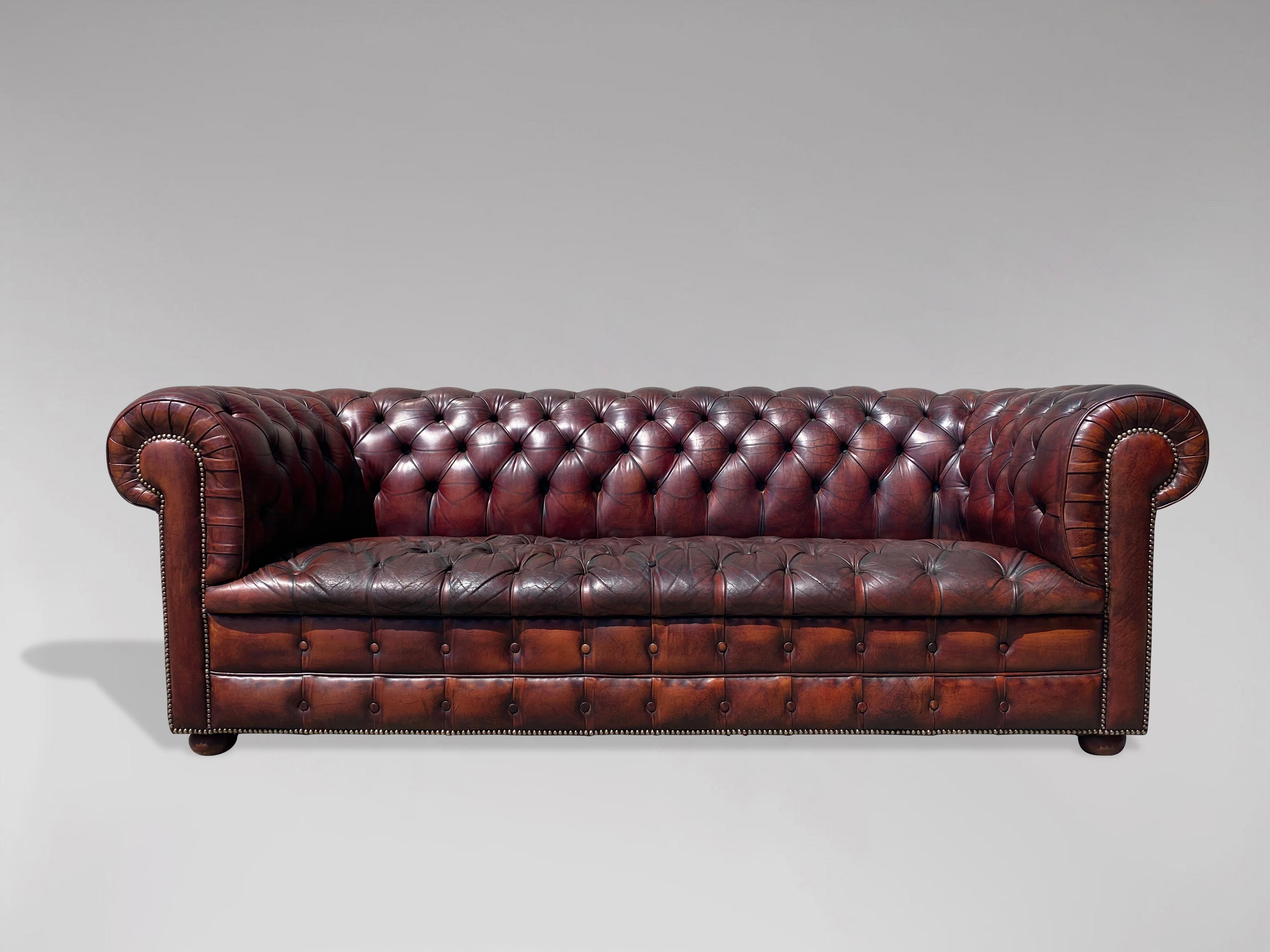 Canapé Chesterfield en cuir bordeaux à trois places du début du 20e siècle. La peau d'origine en cuir brun rouge a été nettoyée et polie, ce qui donne une sensation de douceur et de somptuosité à ce cuir de qualité. Il est doté d'un siège