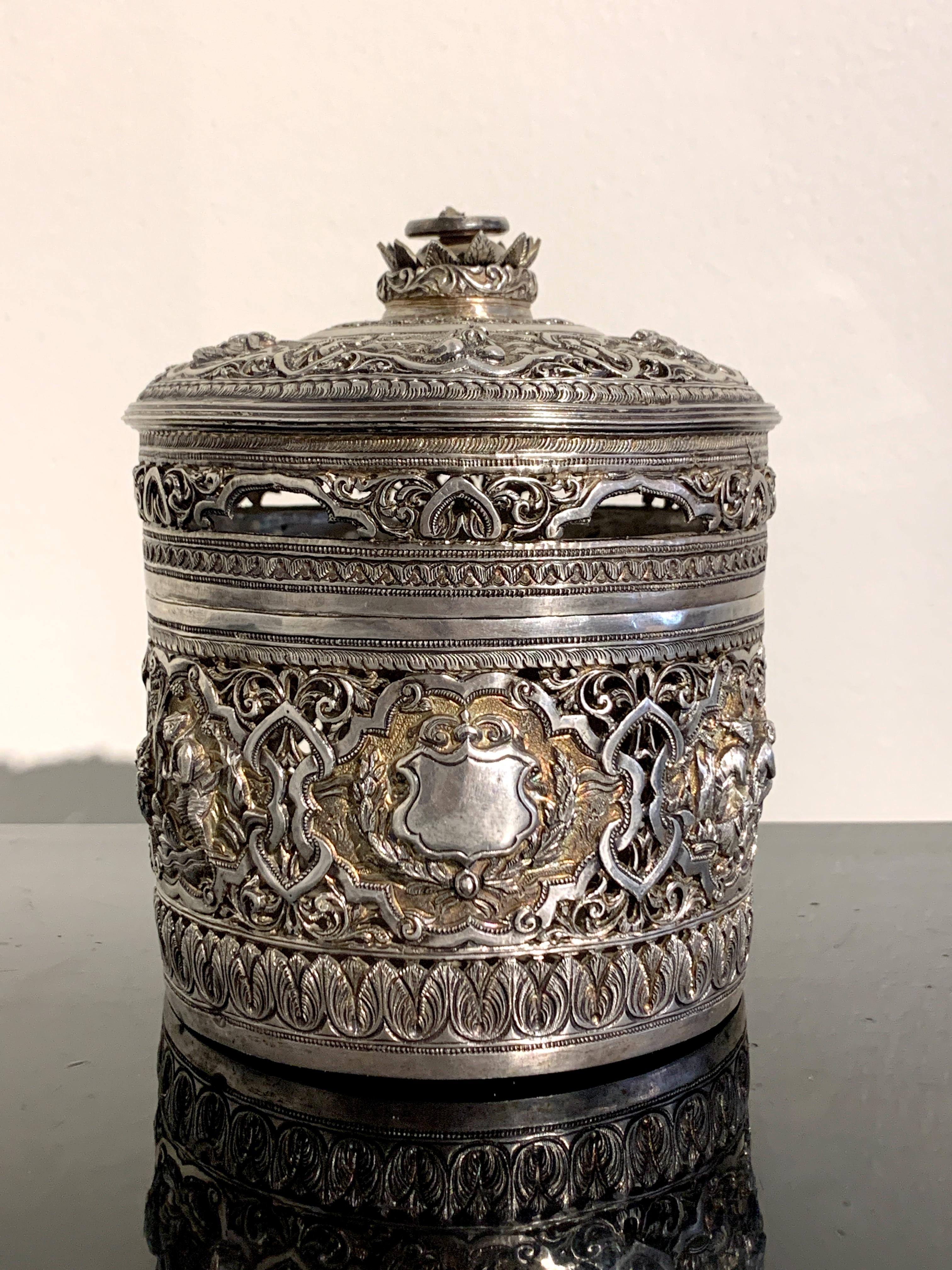 A very fine Burmese Colonial Period betel presentation box of pierced and repoussé silver with parcel gilding, early 20th century, Burma (Myanmar). 

The round betel box in three parts, consisting of the lid, interior tray, and box, expertly
