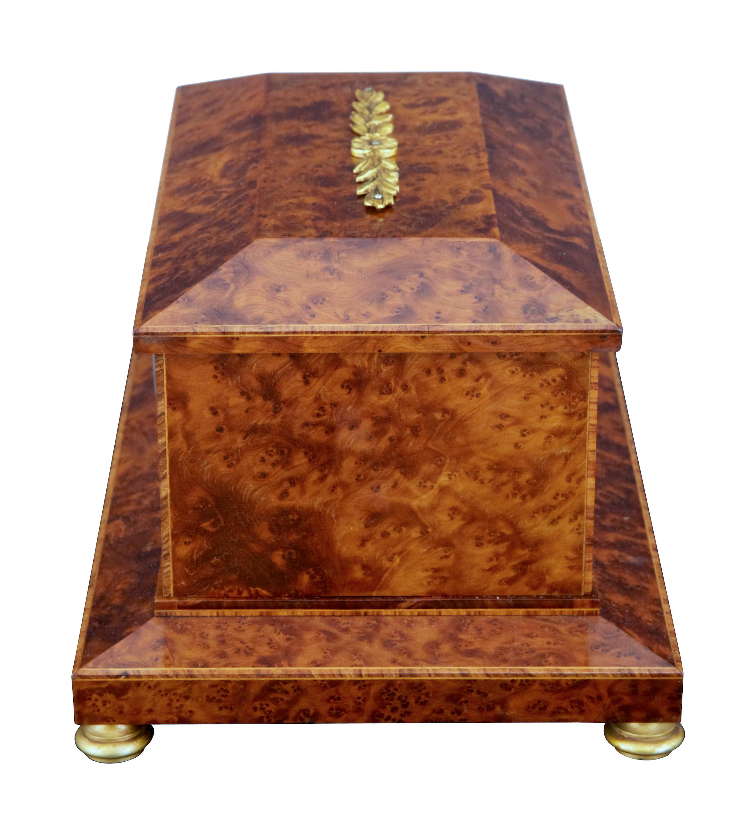 Early 20th century burr yew cigar and clock box, circa 1920.

Empire revival burr yew cigar box with clock. Strung and inlaid to outer edges, decorated with an ormolu mount to the lid and standing on ormolu bun feet. Inset white enamel clock face