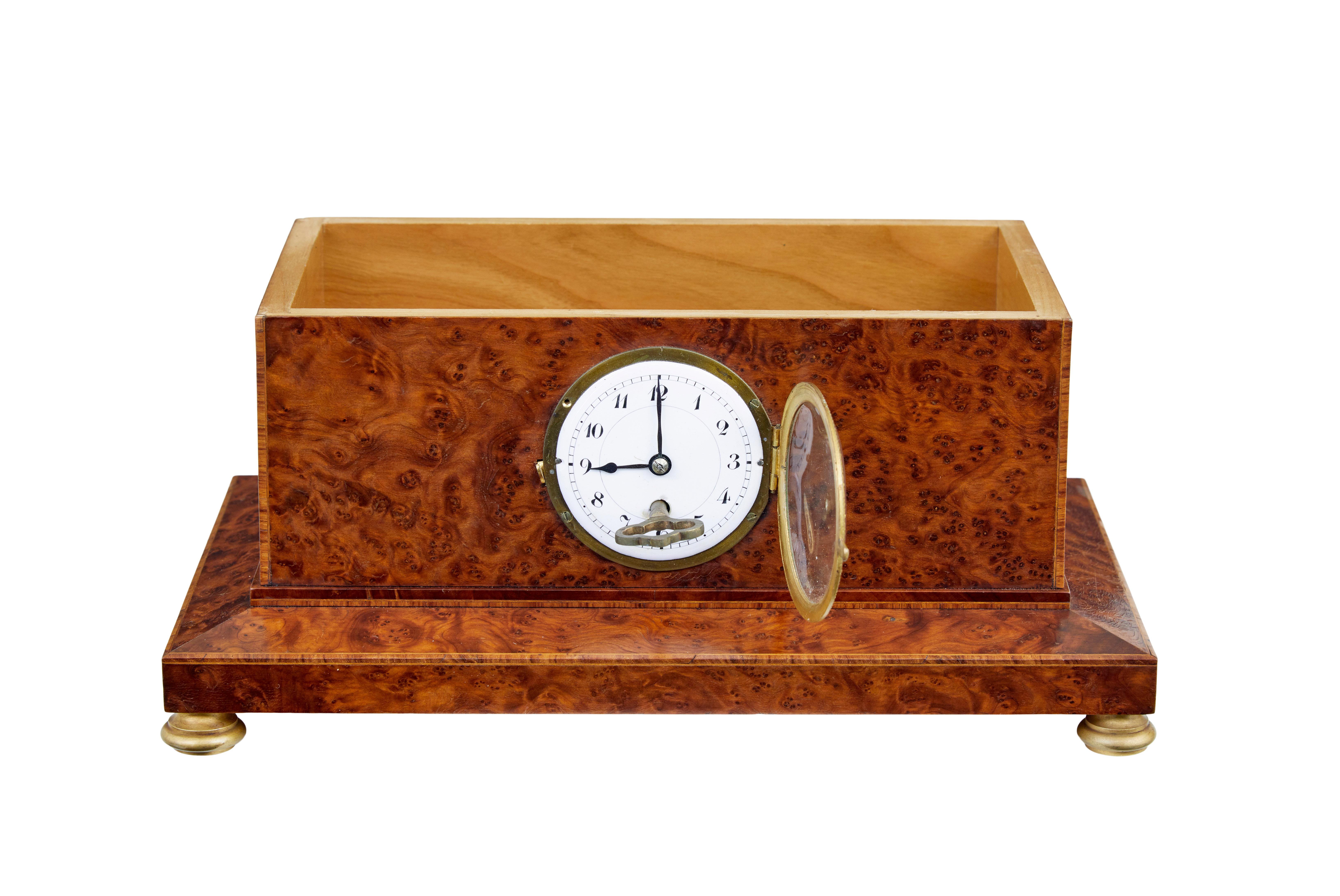 Early 20th century burr yew desktop box with clock circa 1920.

Empire revival burr yew cigar box with clock.  Strung and inlaid to outer edges, decorated with an ormolu mount to the lid and standing on ormolu bun feet.  Inset white enamel clock