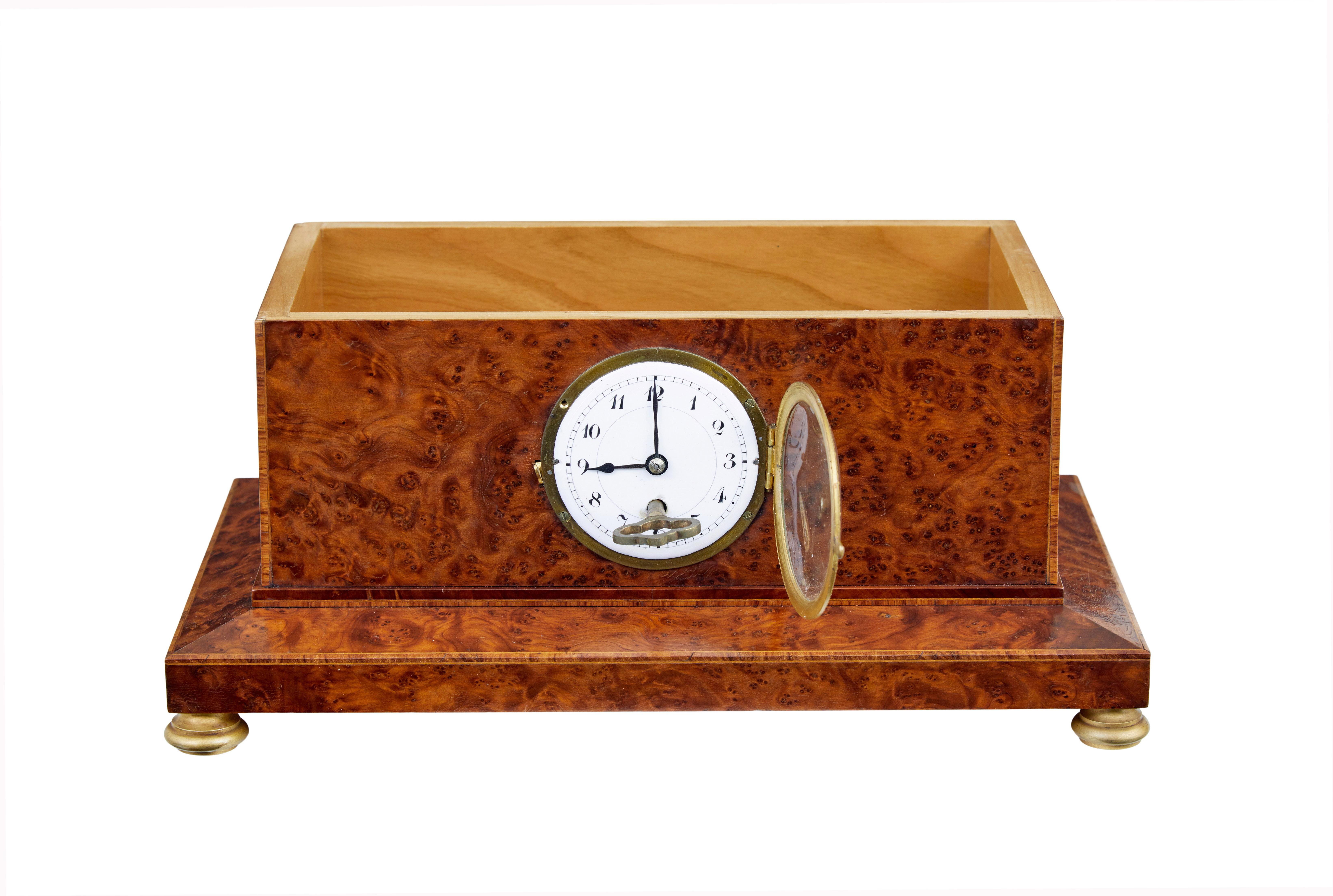 Early 20th century burr yew desktop box with clock circa 1920.

Empire revival burr yew cigar box with clock.  Strung and inlaid to outer edges, decorated with an ormolu mount to the lid and standing on ormolu bun feet.  Inset white enamel clock