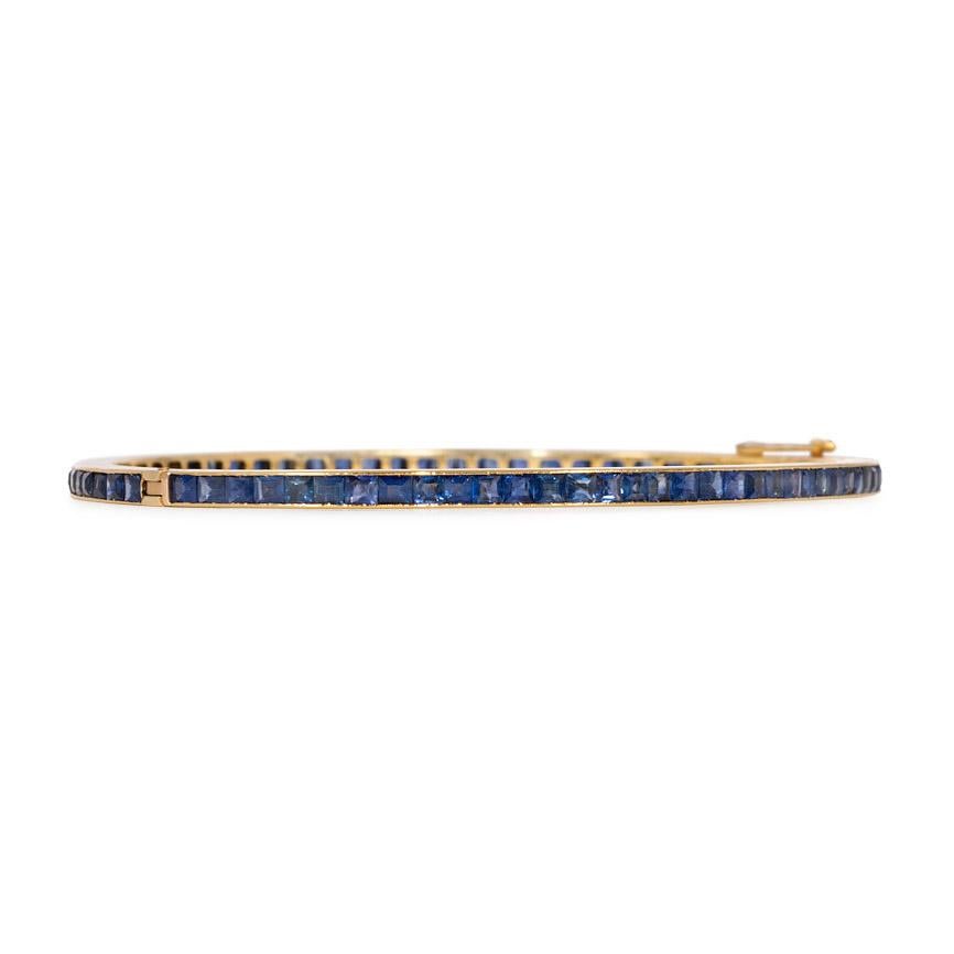 An Edwardian gold bangle bracelet of channel-set calibré sapphires, in 18k.  French import.  In wonderful condition; great stacking bracelet as well as on its own

Inner circumference: approximately 6.75