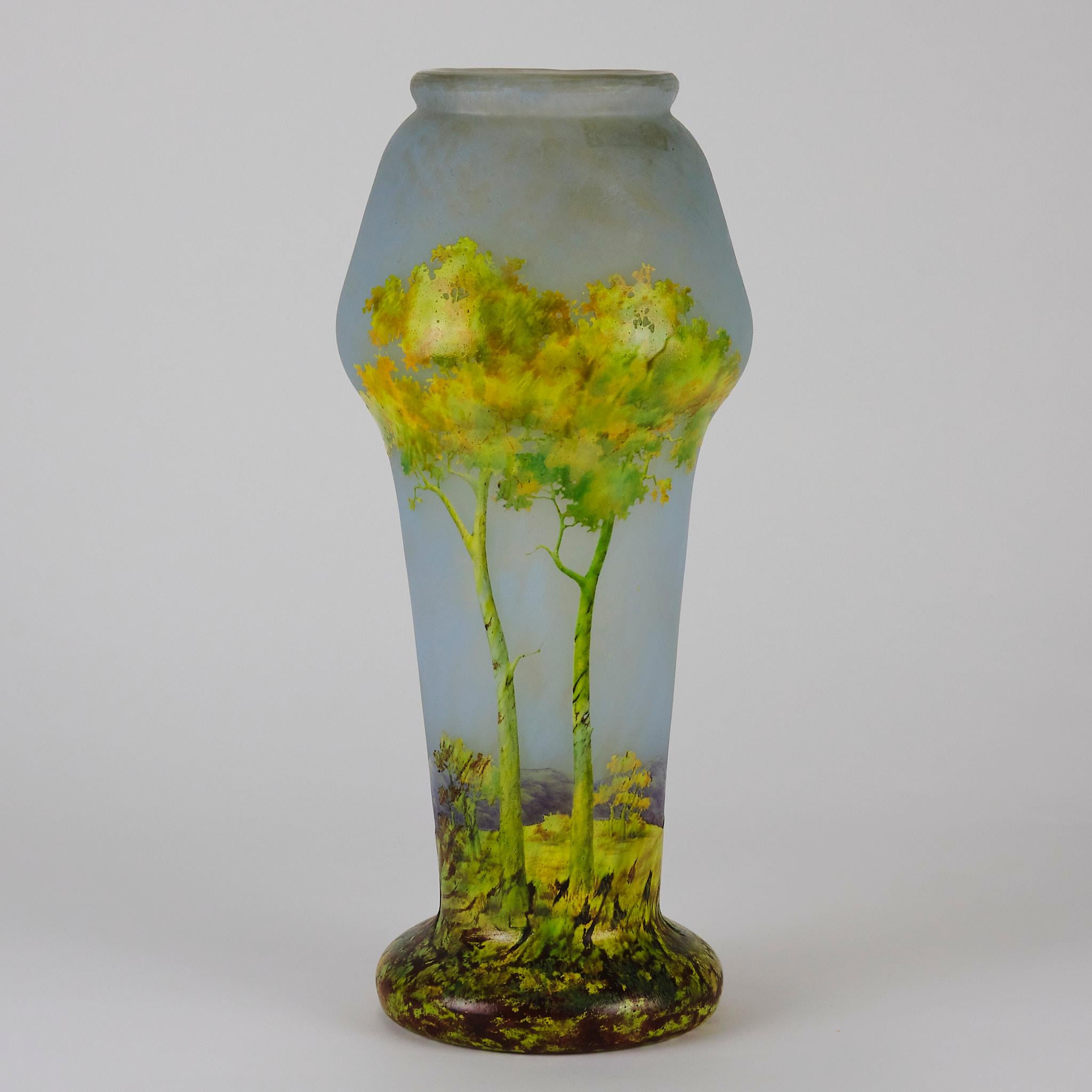 Uno splendido vaso in vetro cammeo inciso e smaltato con alberi dai colori vivaci in primo piano su uno sfondo collinare e un orizzonte azzurro intenso, con colori e dettagli eccellenti, firmato Daum Nancy e siglato SH per l'artista interno Stefan
