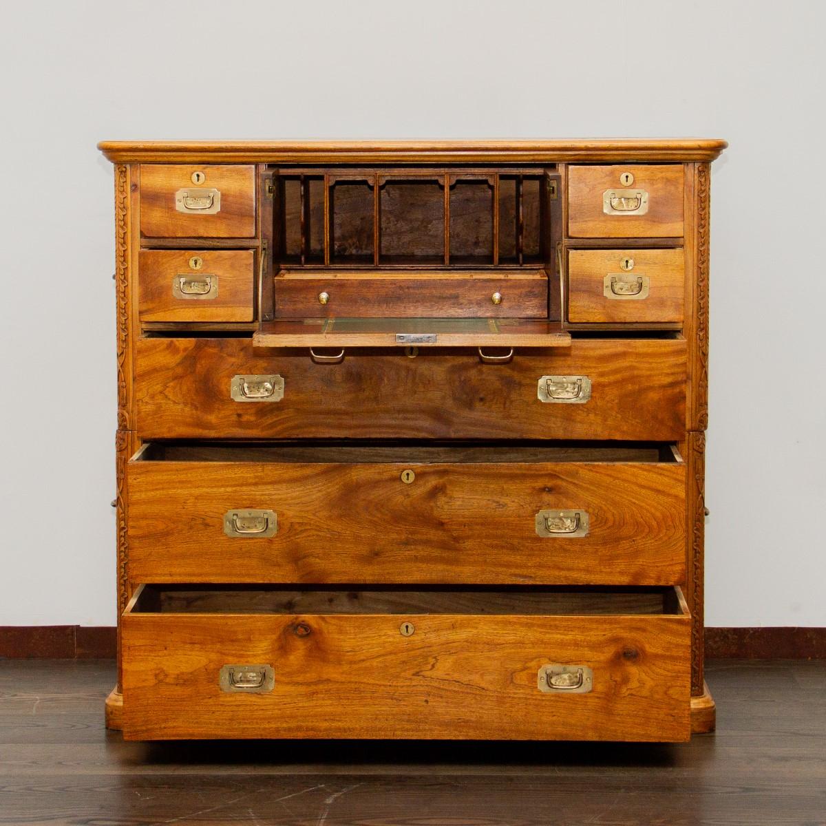 A 20th century camphor wood campaign secretaire chest. The bottom half has two large drawers with flush brass handles, whilst the top contains a single large drawer and four small drawers flanking a drop down desk, all with brass flush handles and