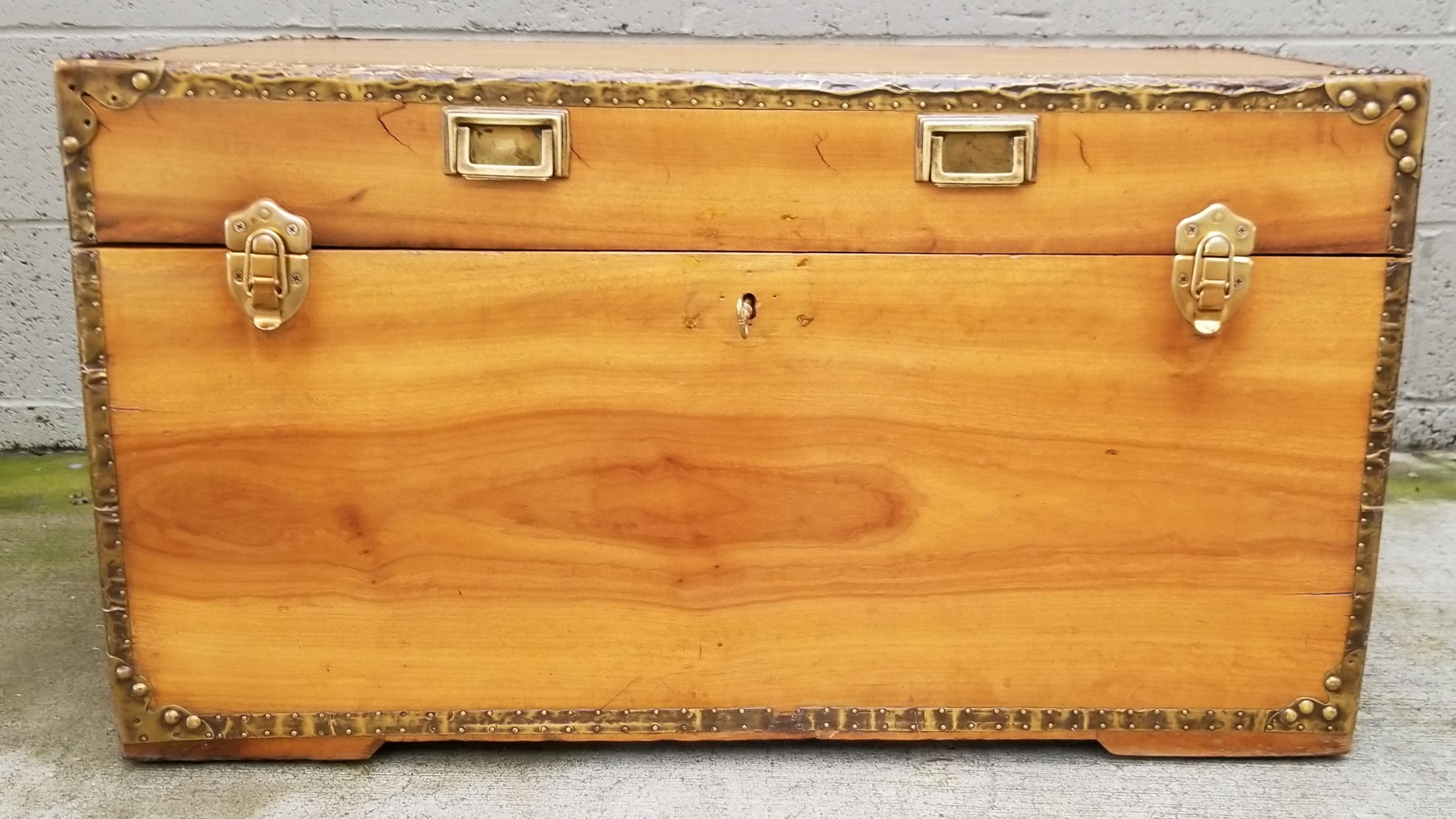 Early 20th century cabin trunk crafted in solid camphor wood with brass-clad edges and brass hardware. Beautiful wood grain throughout. Nice as a coffee table or end table with storage. Key included.