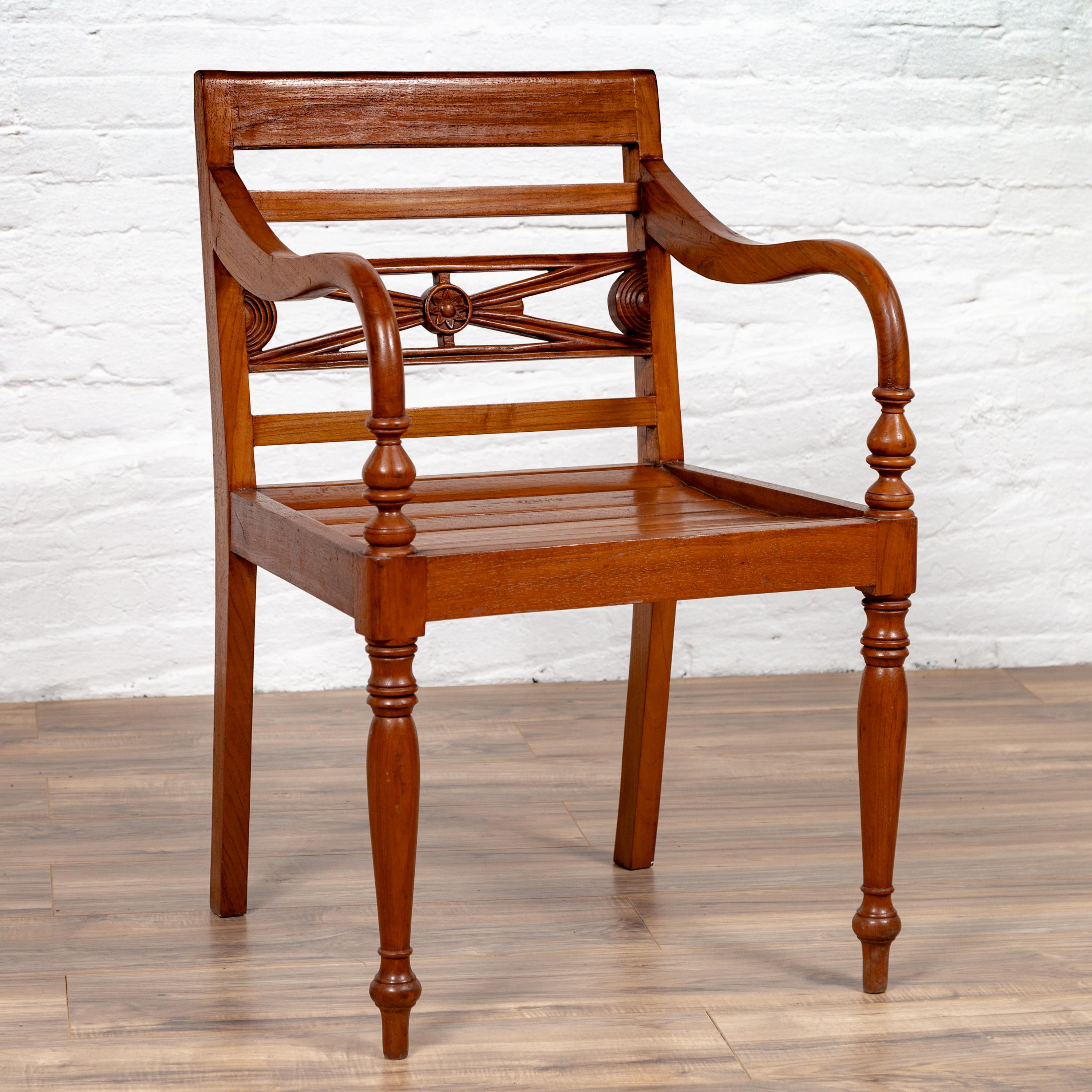 An antique Indonesian captain's chair from the early 20th century, with slatted wood, pierced splat and looping arms. This antique Indonesian captain's chair from the early 20th century is a standout piece with its slatted wood construction,