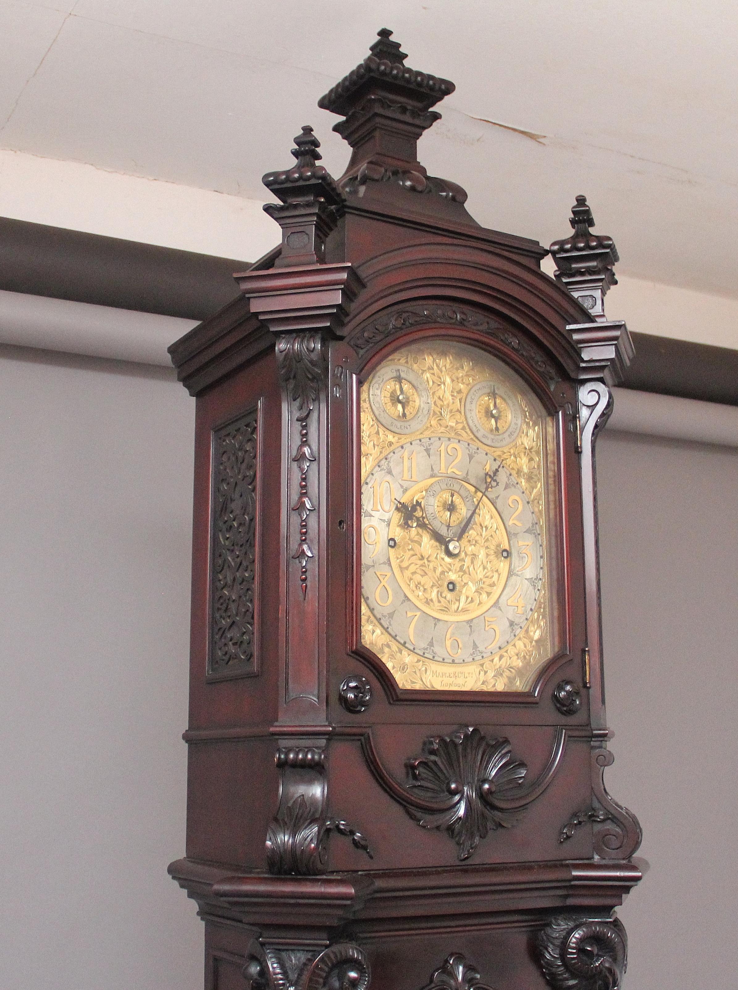Un magnifico orologio a cassa lunga in mogano di Maple & Co. di Londra, di eccellente qualità, con una favolosa cassa in mogano intagliato che incorpora varie decorazioni a conchiglia, foglie e volute intagliate con patere circolari e teste di
