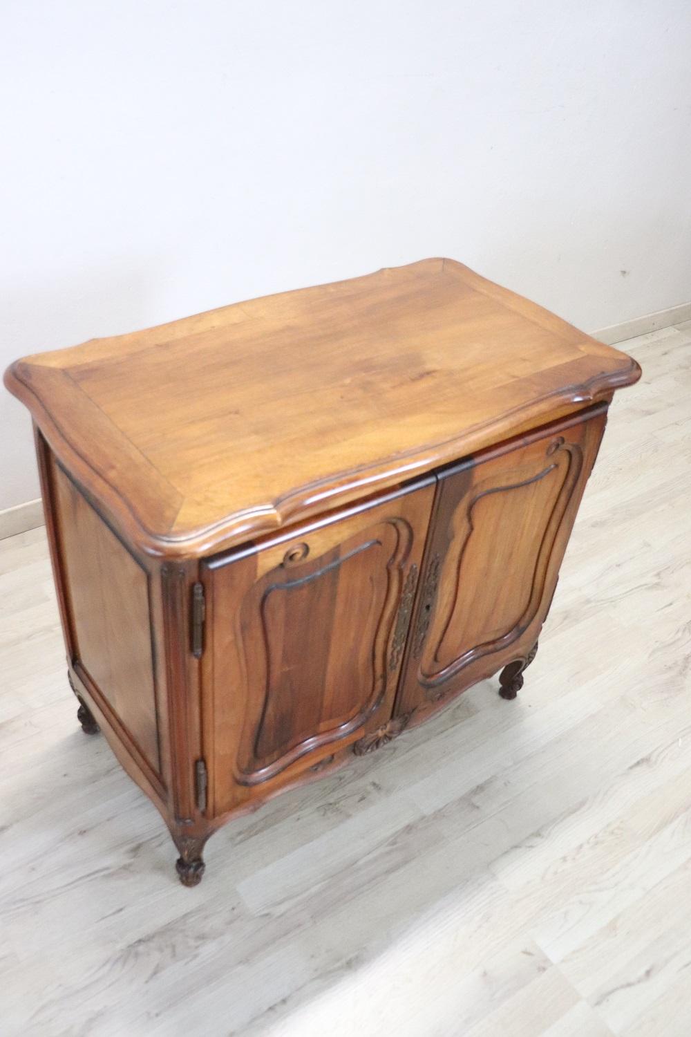 Lovely Small cabinet in solid walnut. Characterized by carving in the doors, elegant and wavy feet. Finished on each side so it can also be placed in the center of the room. Perfect conditions. There are no internal shelves but if necessary we can