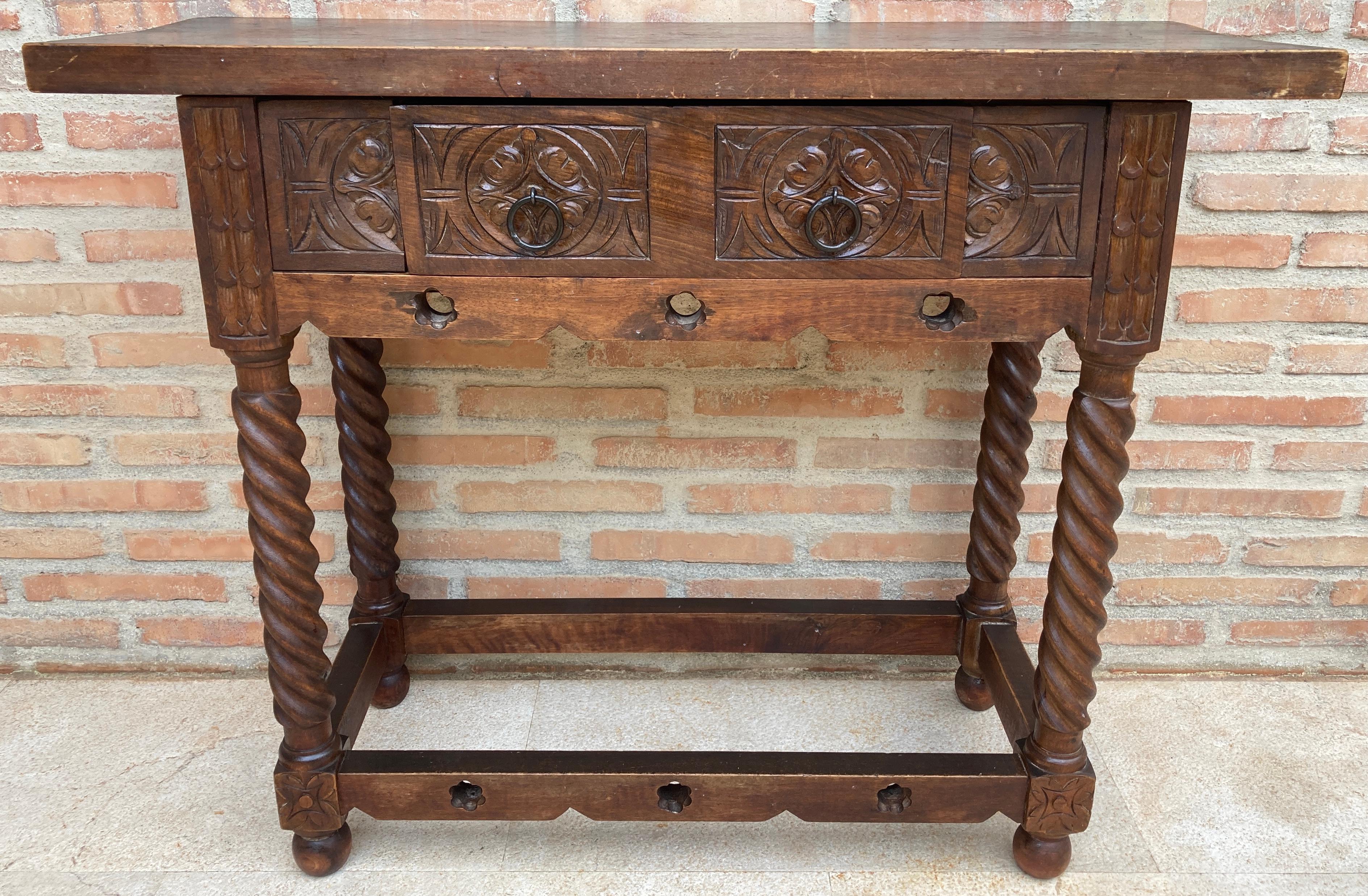 Early 20th century walnut console table with slab top on a frieze with one drawer front decorated with carved and incised floral motifs with additional decoration and two original iron pulls . The table rests on a hand-carved base with Solomonic