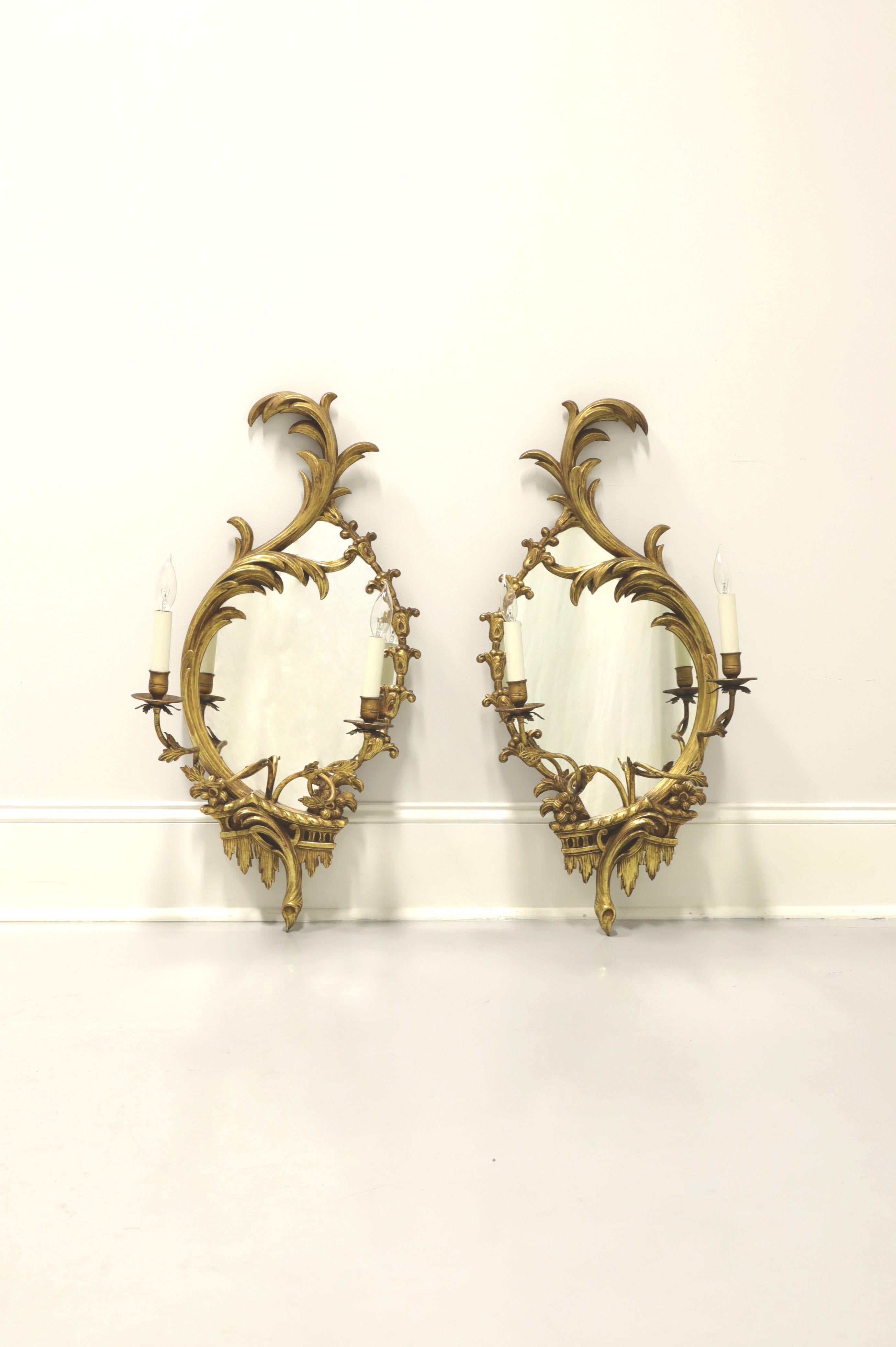 A pair of antique Baroque style electrified candle mirror wall sconces, unbranded. Mirror glass, wood frame, metal arms, brass candleholders, bulb sleeves and small bulb sockets. Features gold painted decoratively carved wood frame and scultped