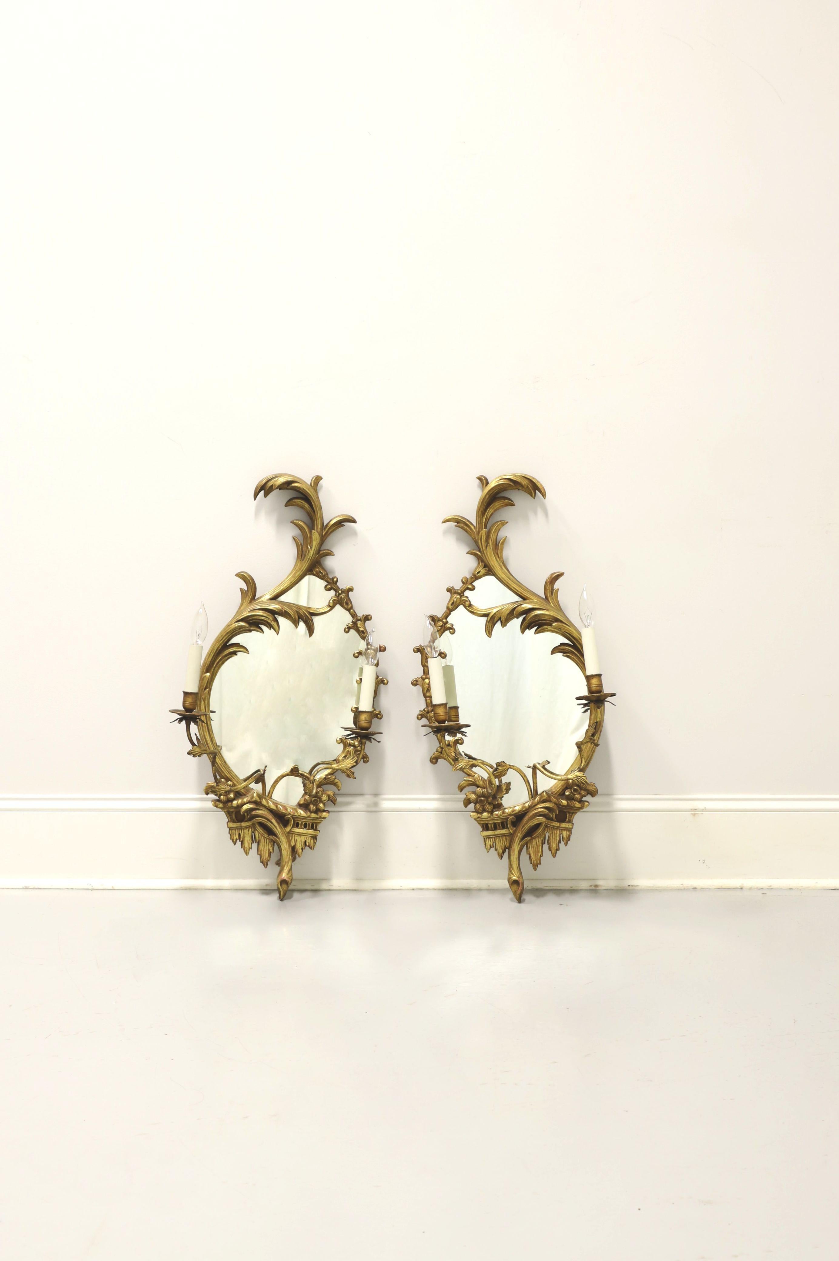 A pair of antique Baroque style electrified candle mirror wall sconces, unbranded. Mirror glass, wood frame, metal arms, brass candleholders, bulb sleeves and small bulb sockets. Features gold painted decoratively carved wood frame and scultped