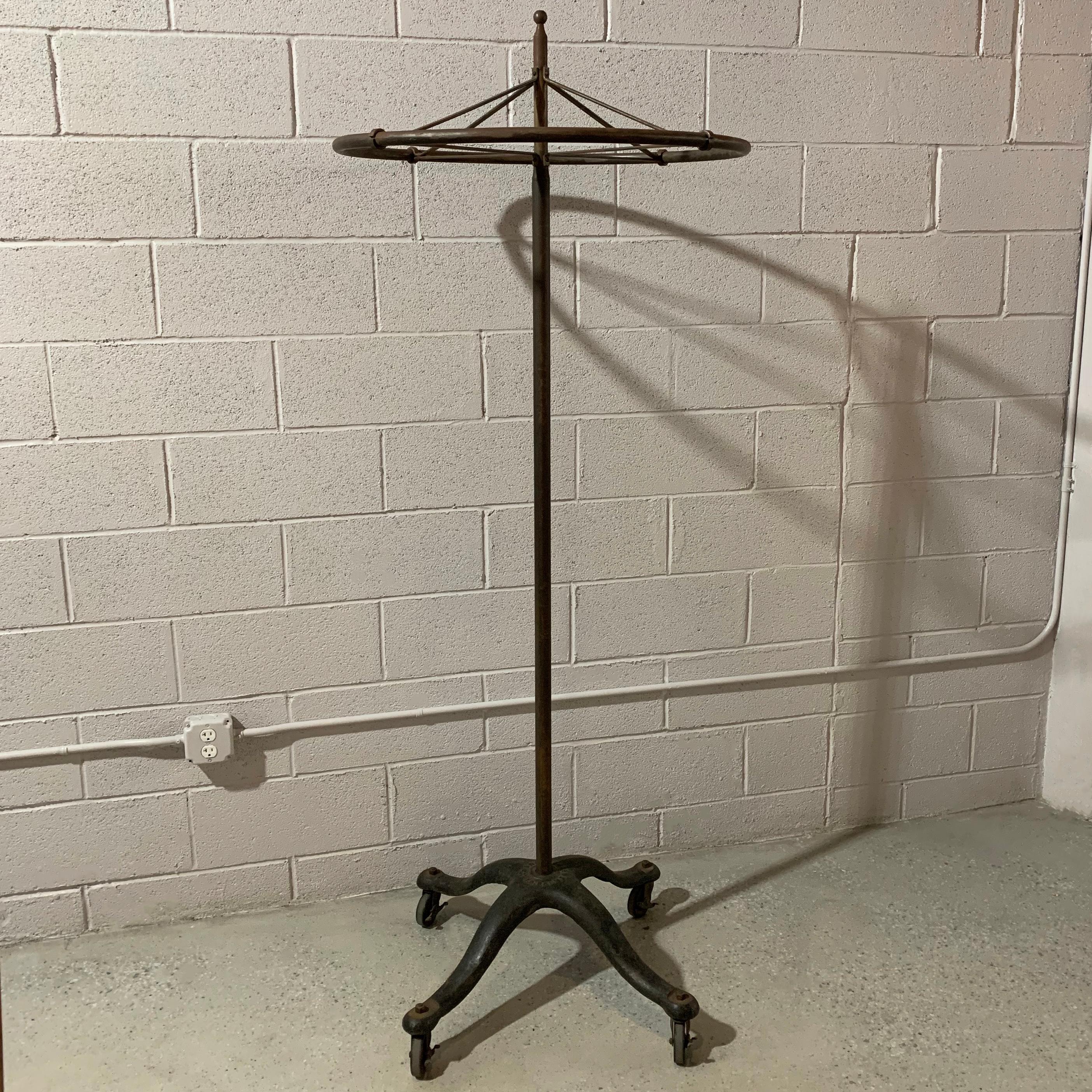 Early 20th century, rounder, garment display rack by J.R. Palmenberg's Sons NY features a rolling cast iron base with steel pole and rotating 29 inch diameter carousel.