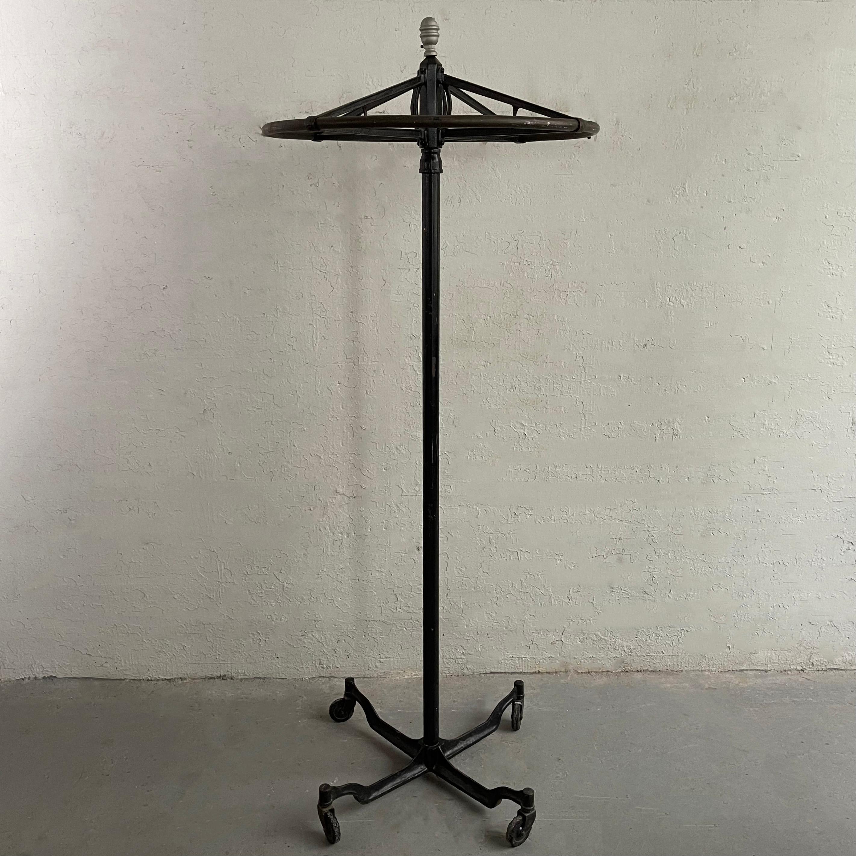 Early 20th century, industrial, cast iron rounder garment rack features a 30 inch round rotating rack on a rolling stem. The round rack separates from the stem for transport.