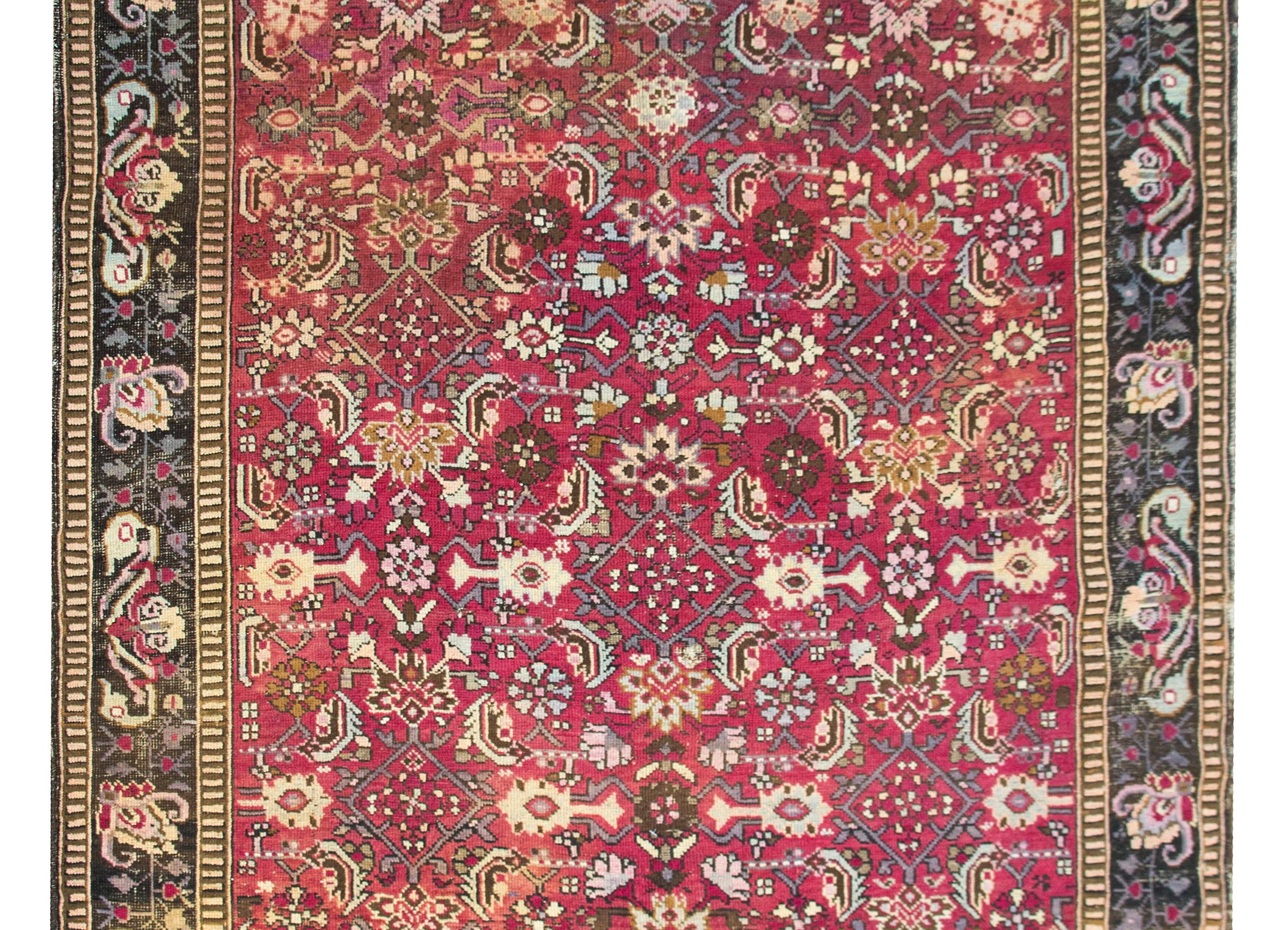 A fantastic early 20th century Caucasian Karabagh rug with an all-over trellis stylized leaf and flower pattern woven in pinks, creams, light indigos, gray, and brown wool set against a cranberry background, and surrounded by a border with more