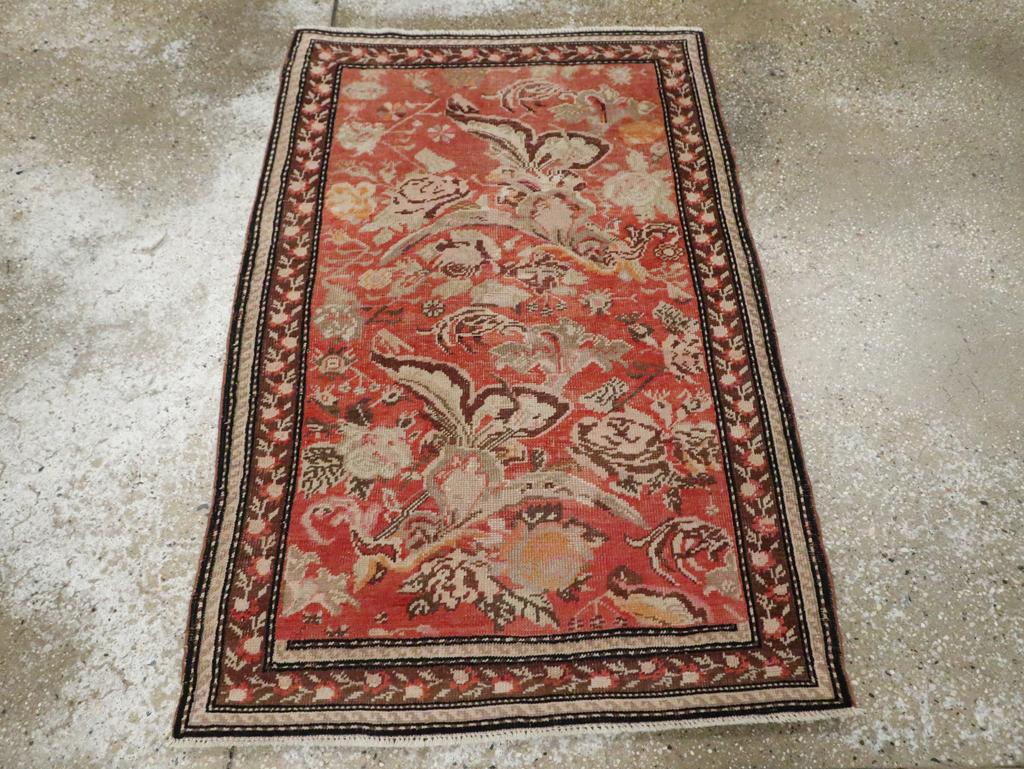 Un tapis ancien du Karabagh, originaire du Caucase. Le fond corail de ce petit tapis du Caucase de l'Ouest est dominé par une double répétition de fleurs baroques, de roses choux et de minuscules grappes florales.  Une chaîne de roses bien rangée