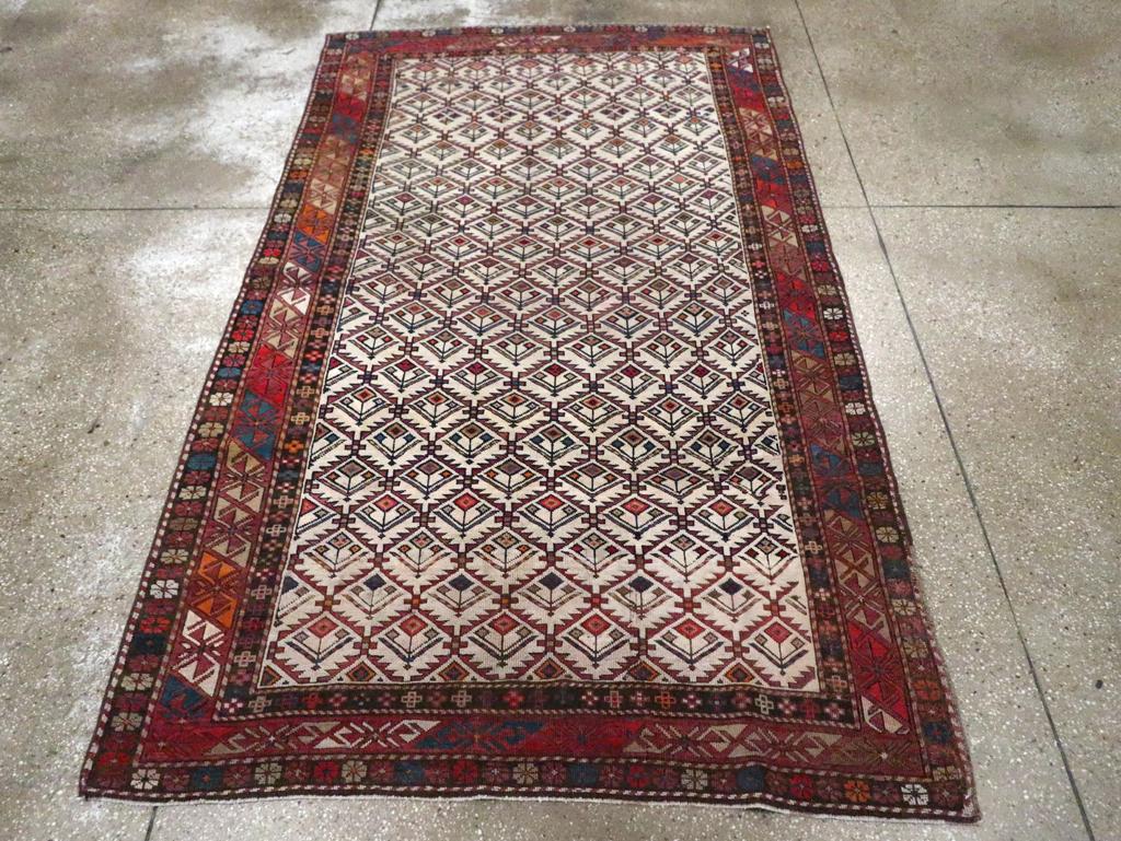 An antique Caucasian Shirvan accent rug. The ivory field is organized by a hexagonal lozenge leaf trellis whose cells each enclose a stylized flower. All flowers point in the same direction. The red border of barred S’s is a Shirvan diagnostic. The