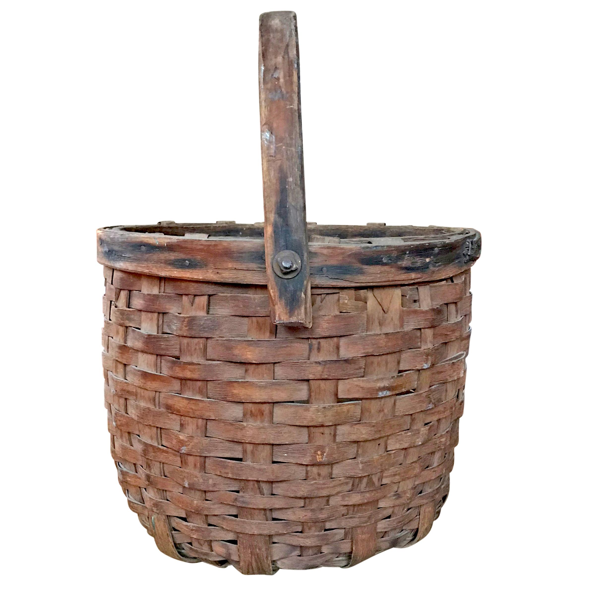 A wonderful early 20th century American handwoven cedar splint gathering basket with a swivel handle attached with bolts, and a heavy double band rim. Found in Wisconsin.