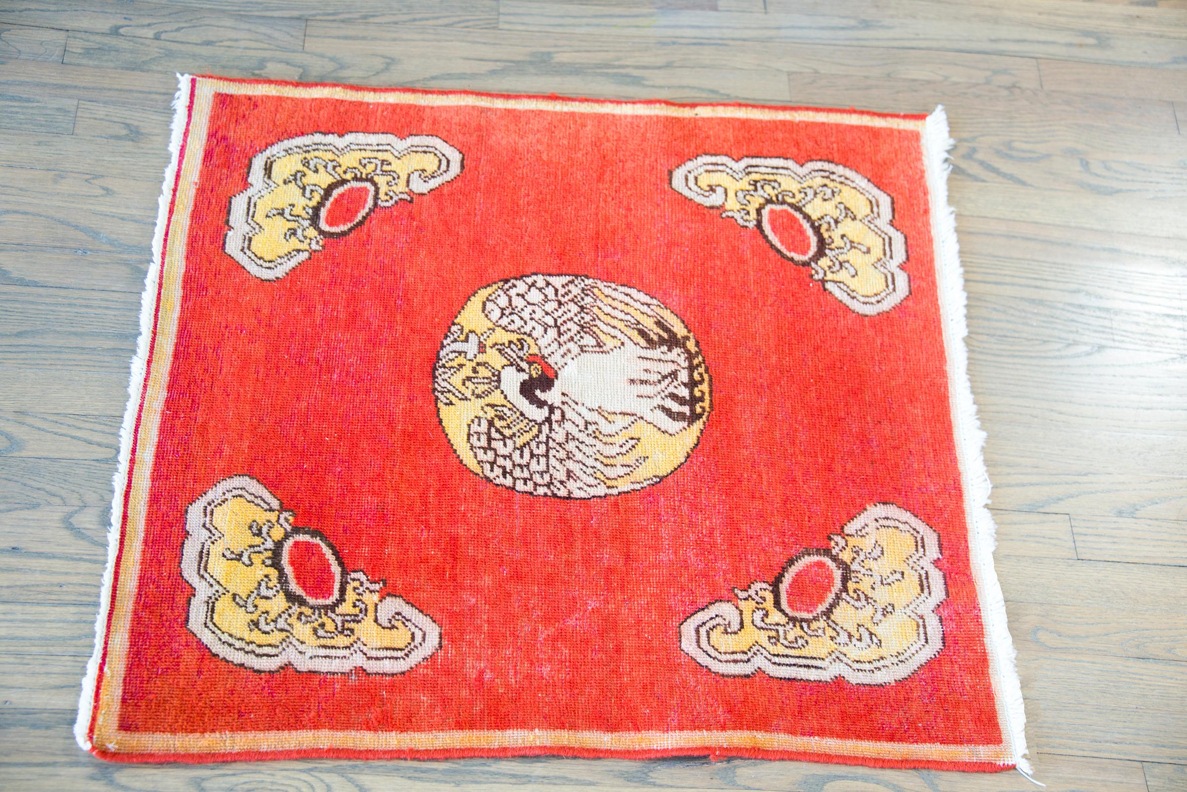 A charming early 20th century Central Asian Khotan rug styled after a traditional Chinese Rank Badge, with a large swan in the center with cloud-form shapes in each corner, and all set against a traditional Khotan orange background.