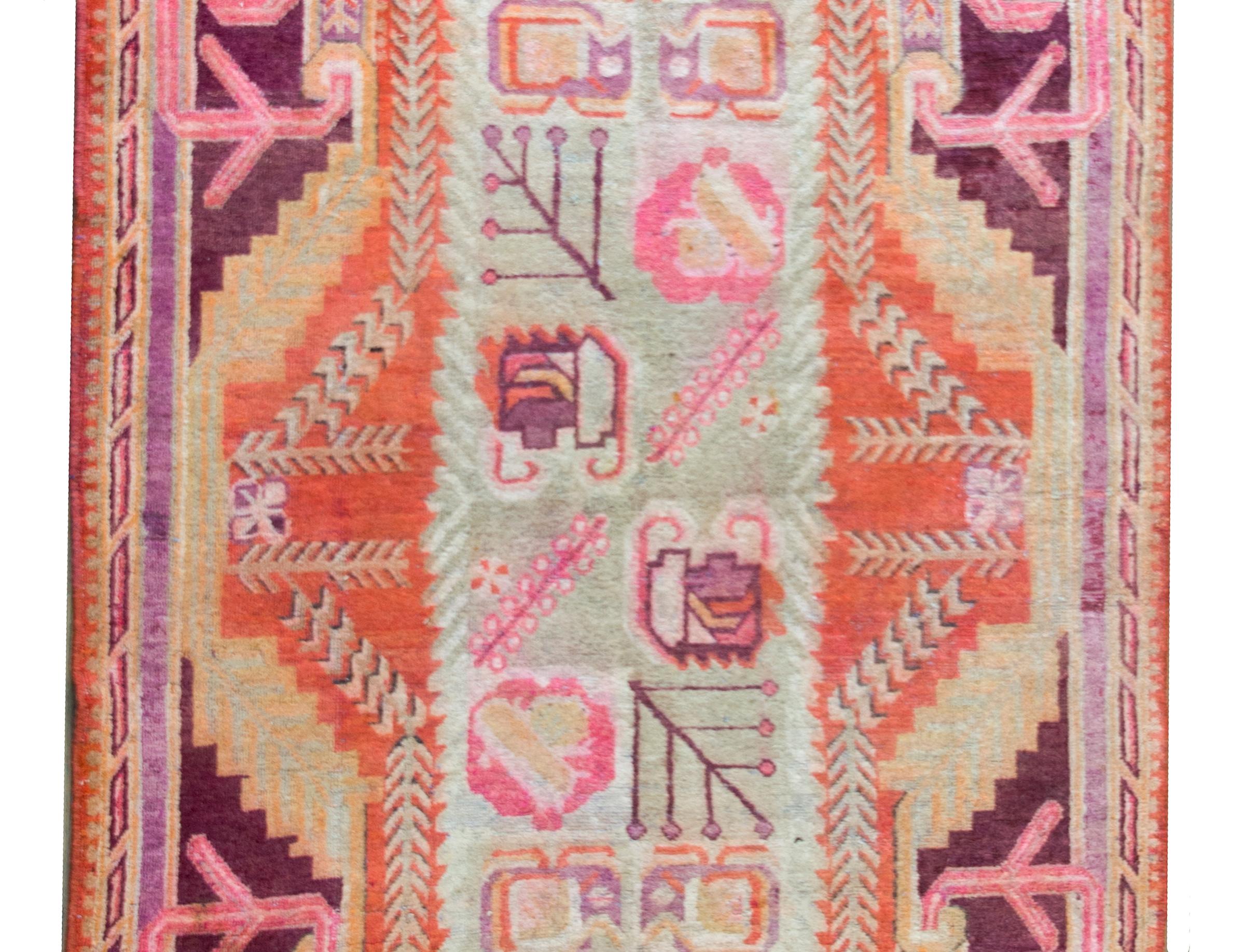 A stunning early 20th century Central Asian Khotan rug with the most wonderful central field with stylized flowers and leaves surrounded by a Baroque styled border with more stylized flowers, and all woven in incredible pinks, mint greens, oranges,