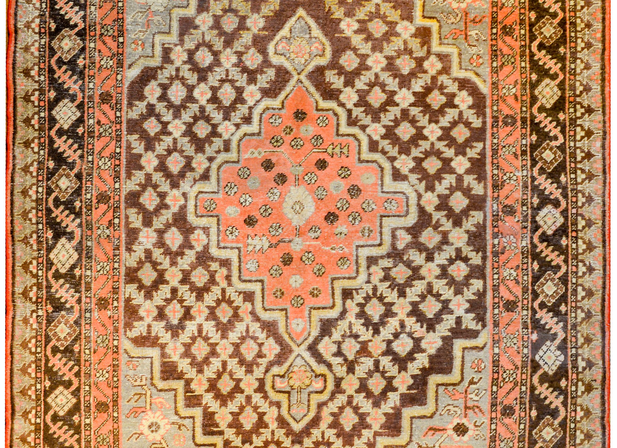 A beautiful early 20th century Central Asian Samarghand rug with a large central stepped diamond medallion with a petite floral pattern on a light coral colored background. The medallion lives amidst a trellis and floral pattern on a brown ground.