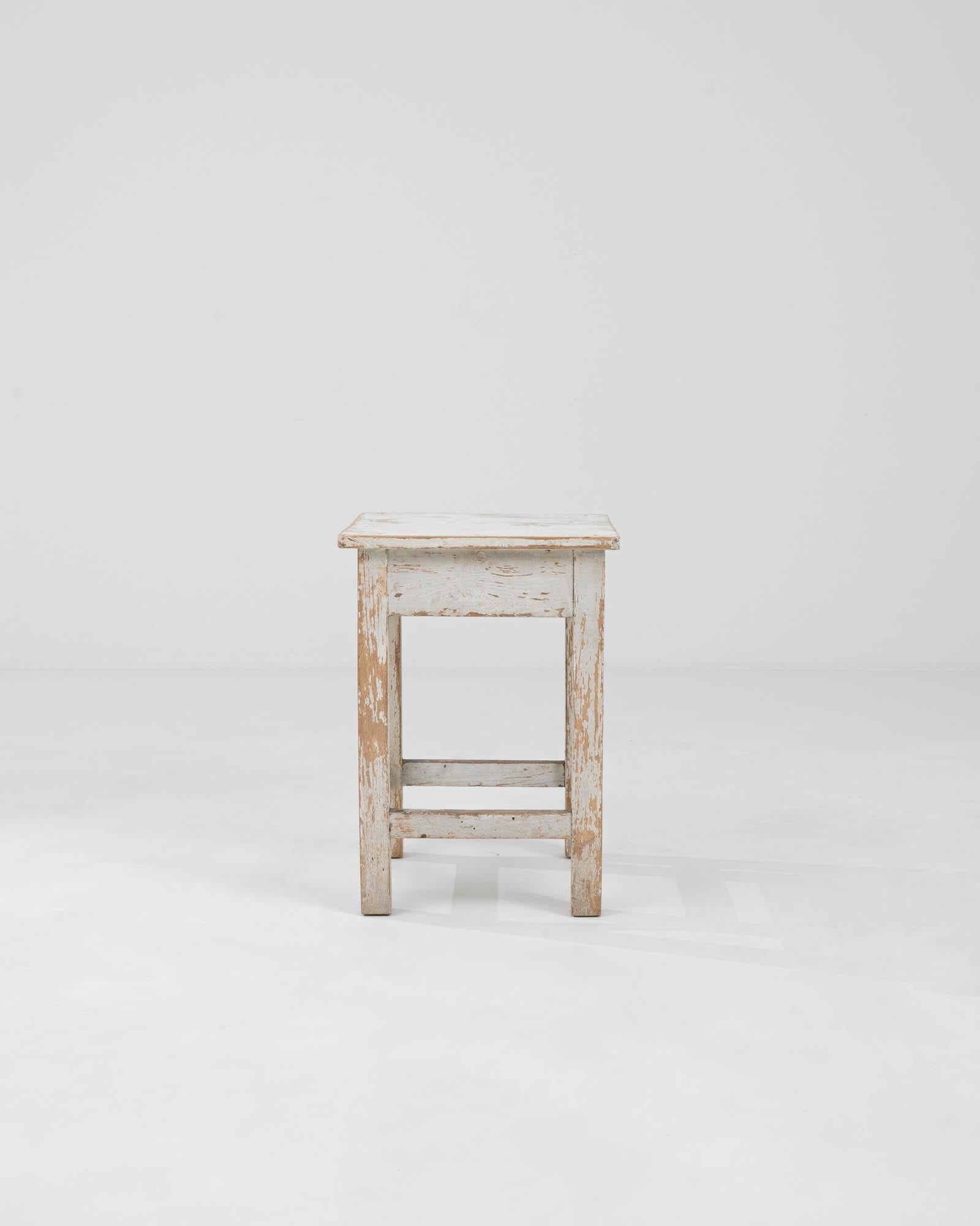 Embrace rustic charm with this Early 20th Century Central European Wood Patinated Stool. Its character-filled patina tells a story of years gone by, making it not just a piece of furniture, but a snippet of history. The stool's weathered white