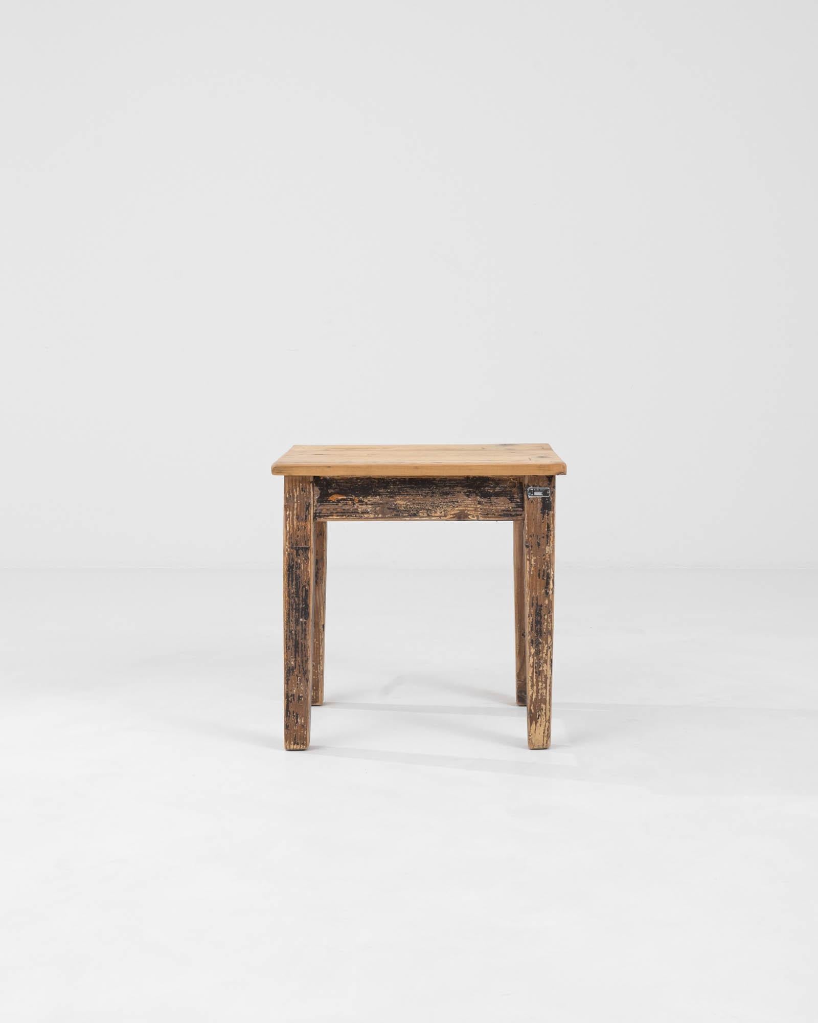 This Early 20th Century Central European stool exudes a sense of history and character. Its wood construction showcases a deep, rich patina, a testament to its age and the stories it must hold. The texture of the wood, grooved and worn, reflects its