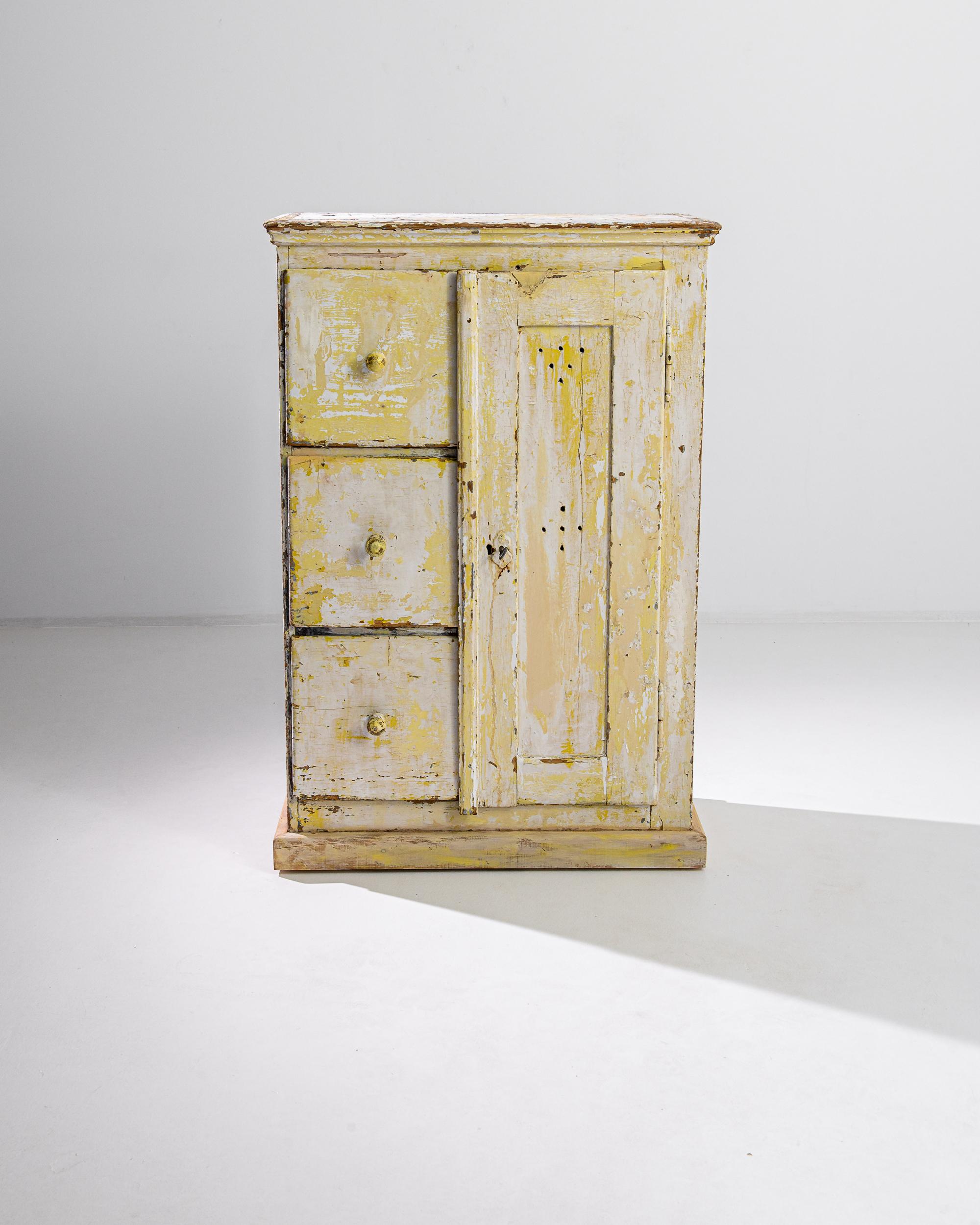 Crafted in Central Europe circa 1900, this wooden buffet flaunts the textural richness of its beautifully distressed finish, with the blurs of yellow patina emerging on the wooden surface. The plinth base and molded top frame the case divided by