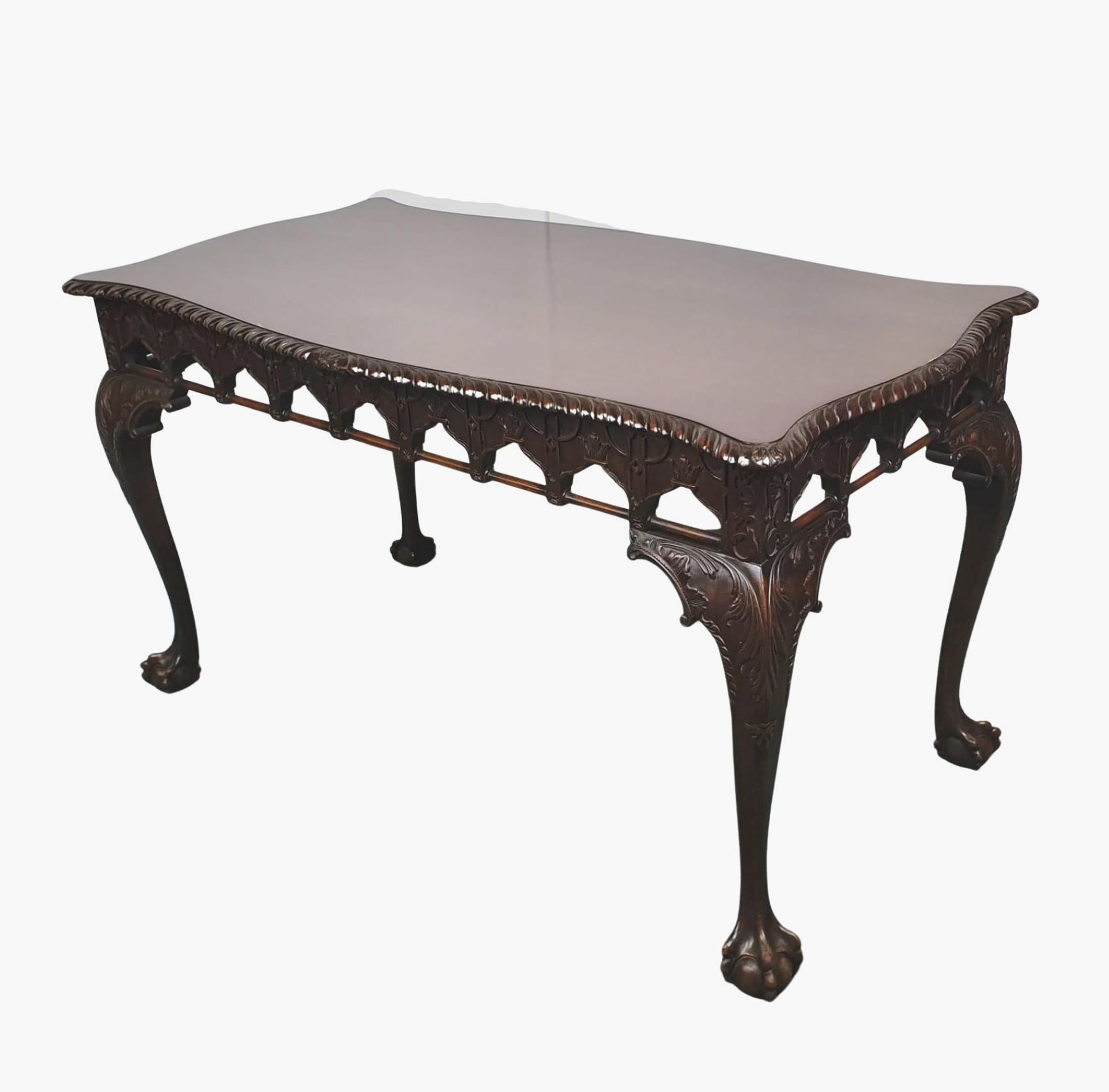 Magnifique table centrale en acajou du début du 20e siècle, de style gothique Chippendale. Le plateau façonné et mouluré de forme rectangulaire avec un bord godronné sculpté et un motif de feuillage centré est surmonté d'une frise minutieusement